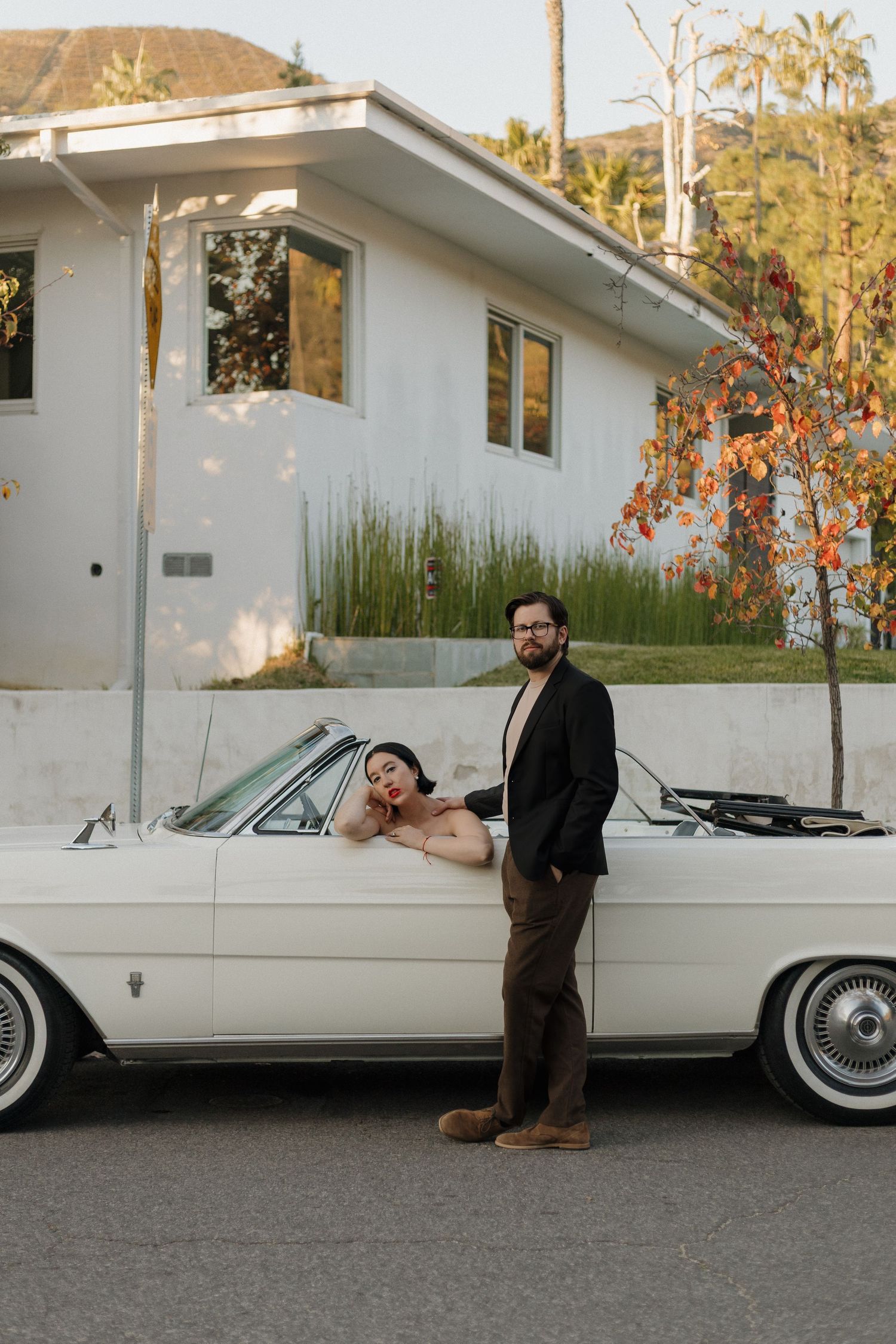 A classic white vintage car serves as backdrop for a stylish couple's photo shoot.