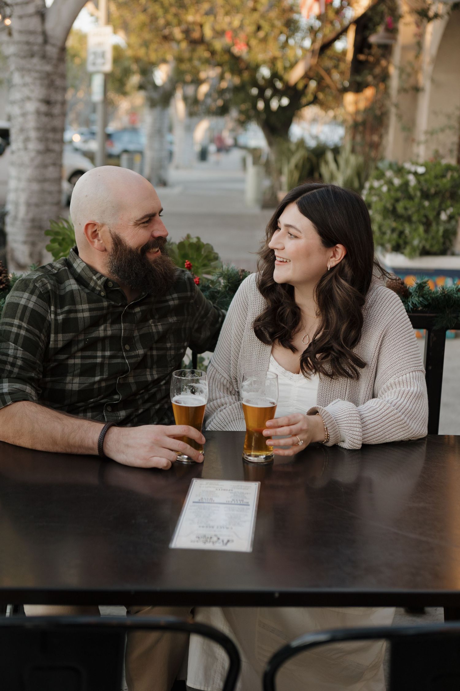 Couple shares drinks and conversation at an outdoor patio table.