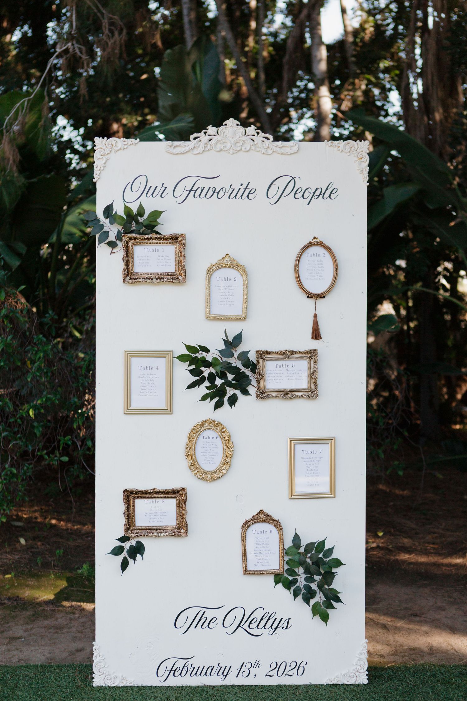 Elegant wedding seating chart board with gold frames and greenery, reading Our Favorite People for The Kellys, February 13th 2026.