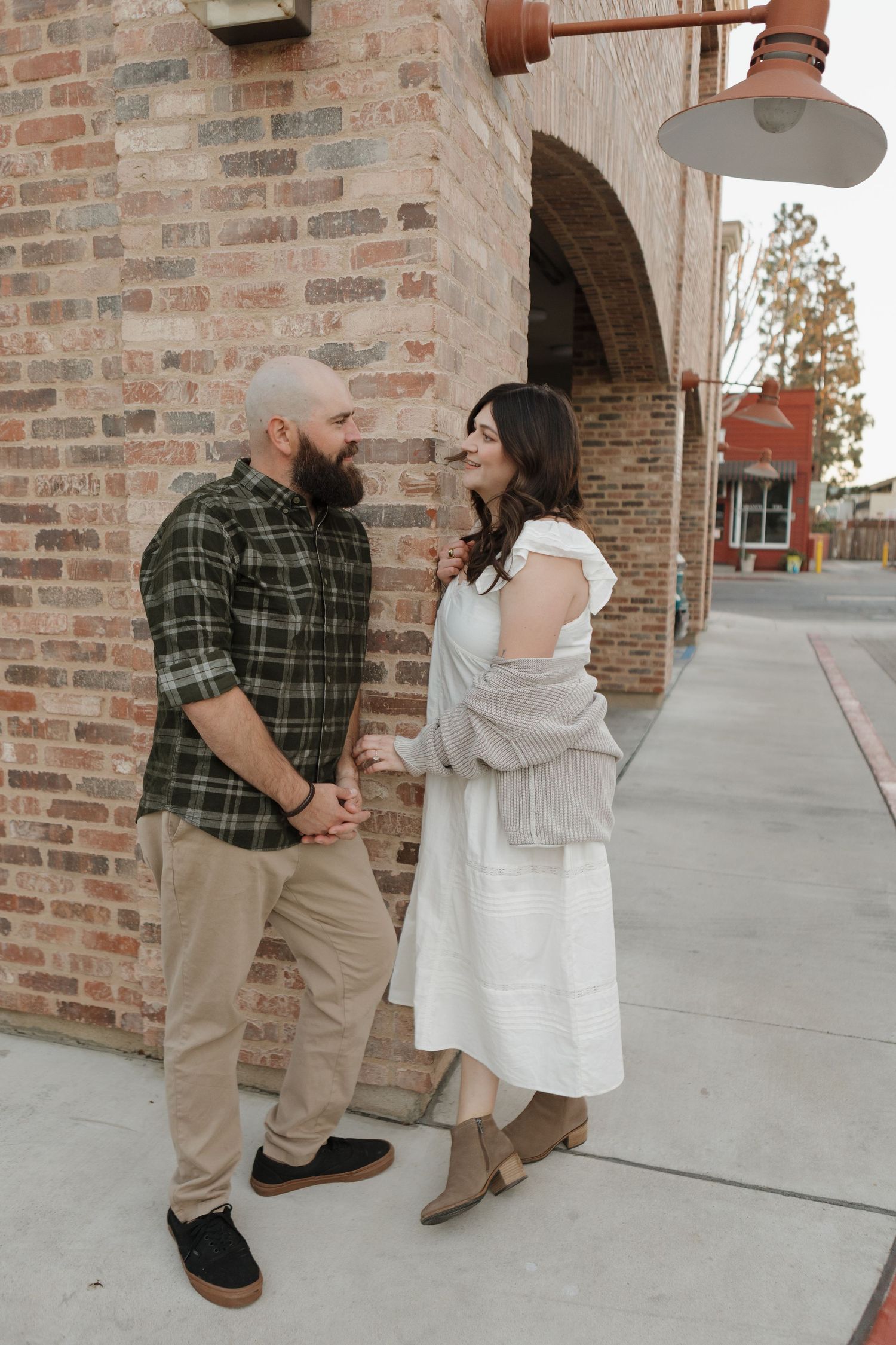 Romantic sequence of a couple dancing together against a brick wall exterior.