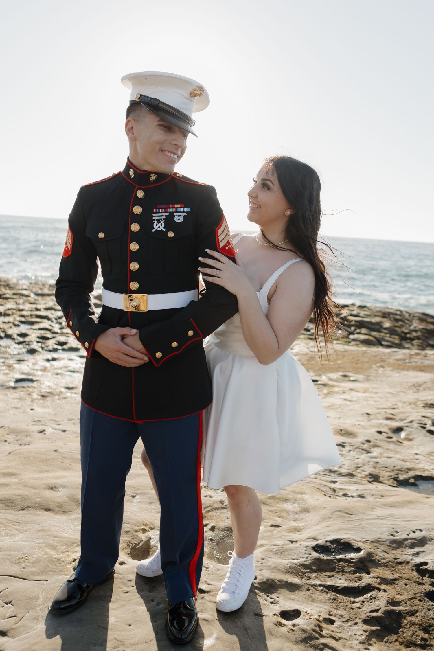 A couple shares an intimate moment on a rocky beach with ocean views.