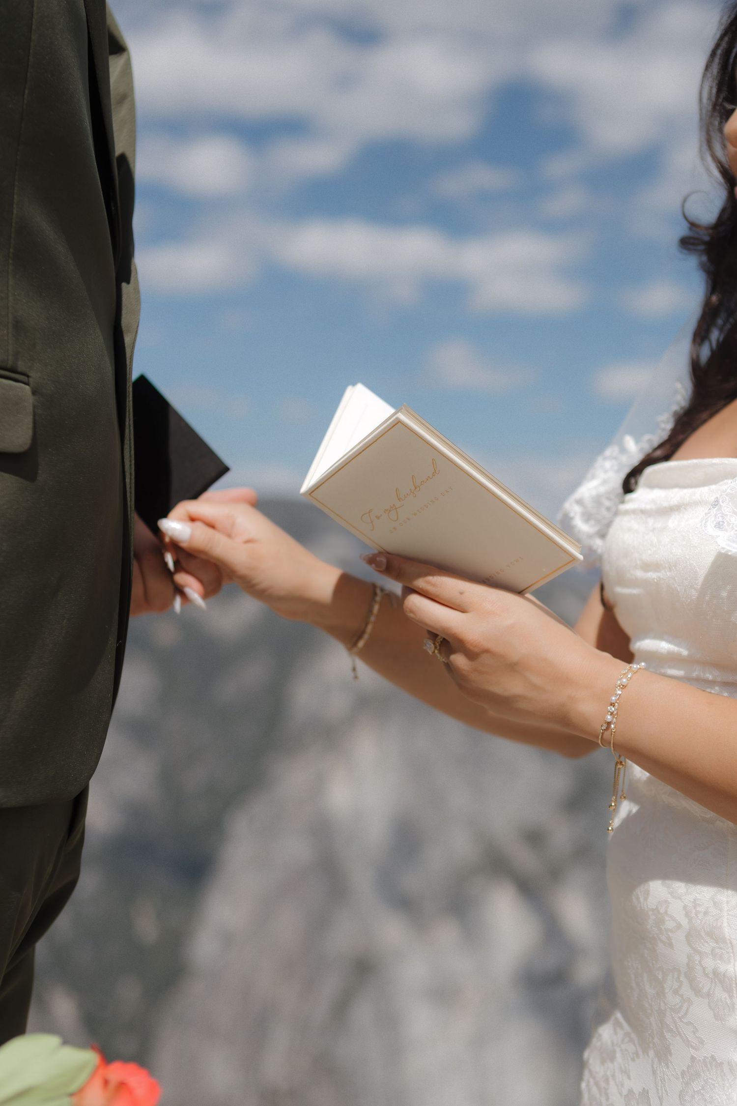Close-up of hands holding papers during an outdoor ceremony against a mountain backdrop.
