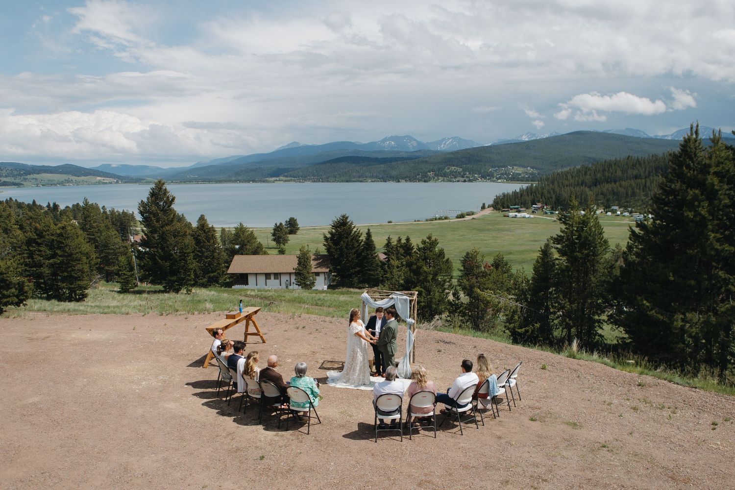 Scenic mountain vista with wedding guests gathered for an outdoor ceremony.