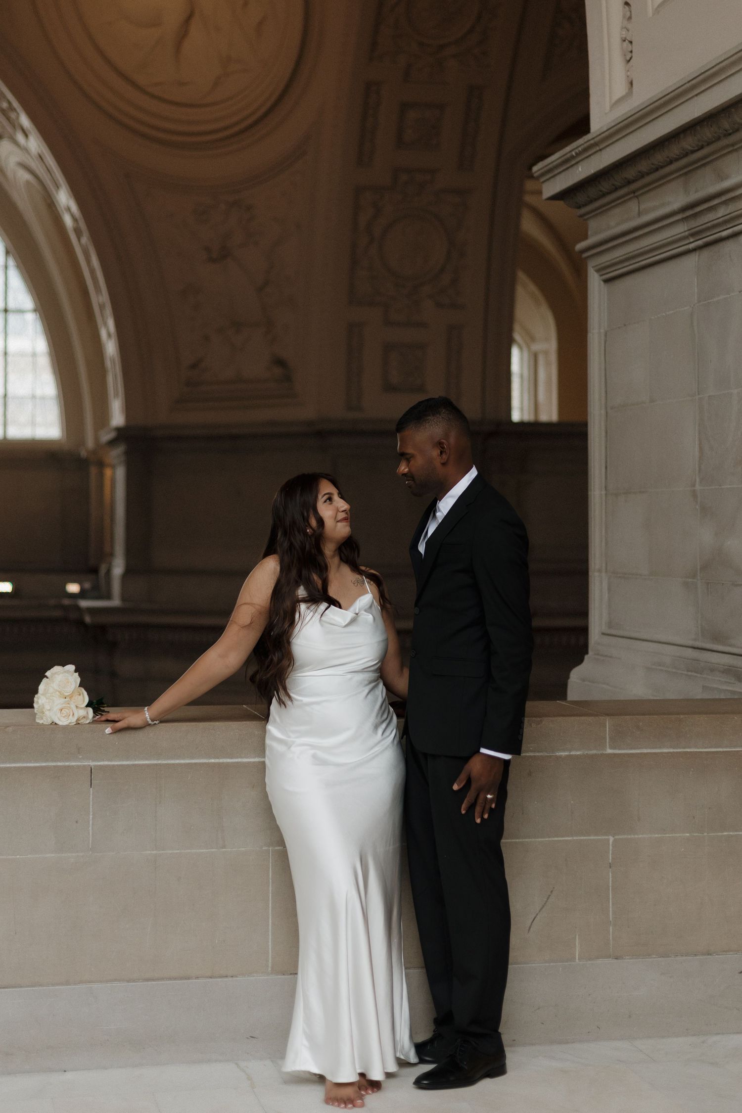 A couple poses for romantic photos in an elegant marble hallway.