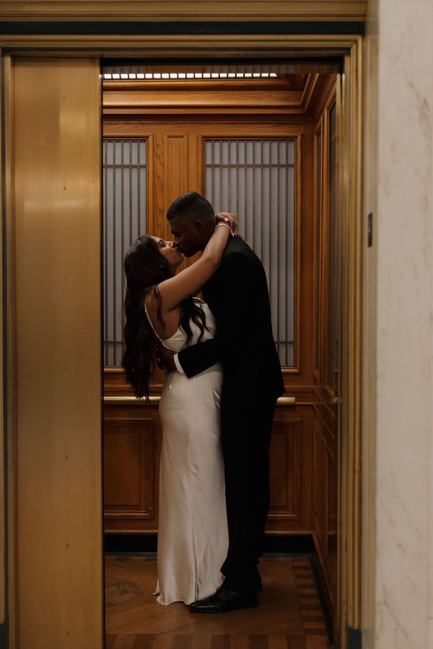 A romantic moment captured in an ornate hallway with wooden details.