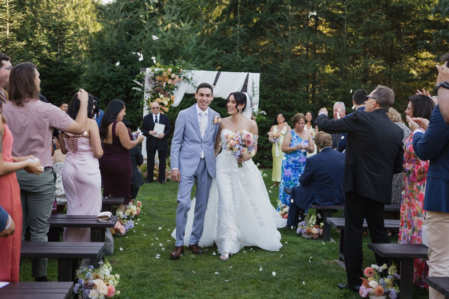 Wedding guests celebrate during an outdoor garden reception with string lights.