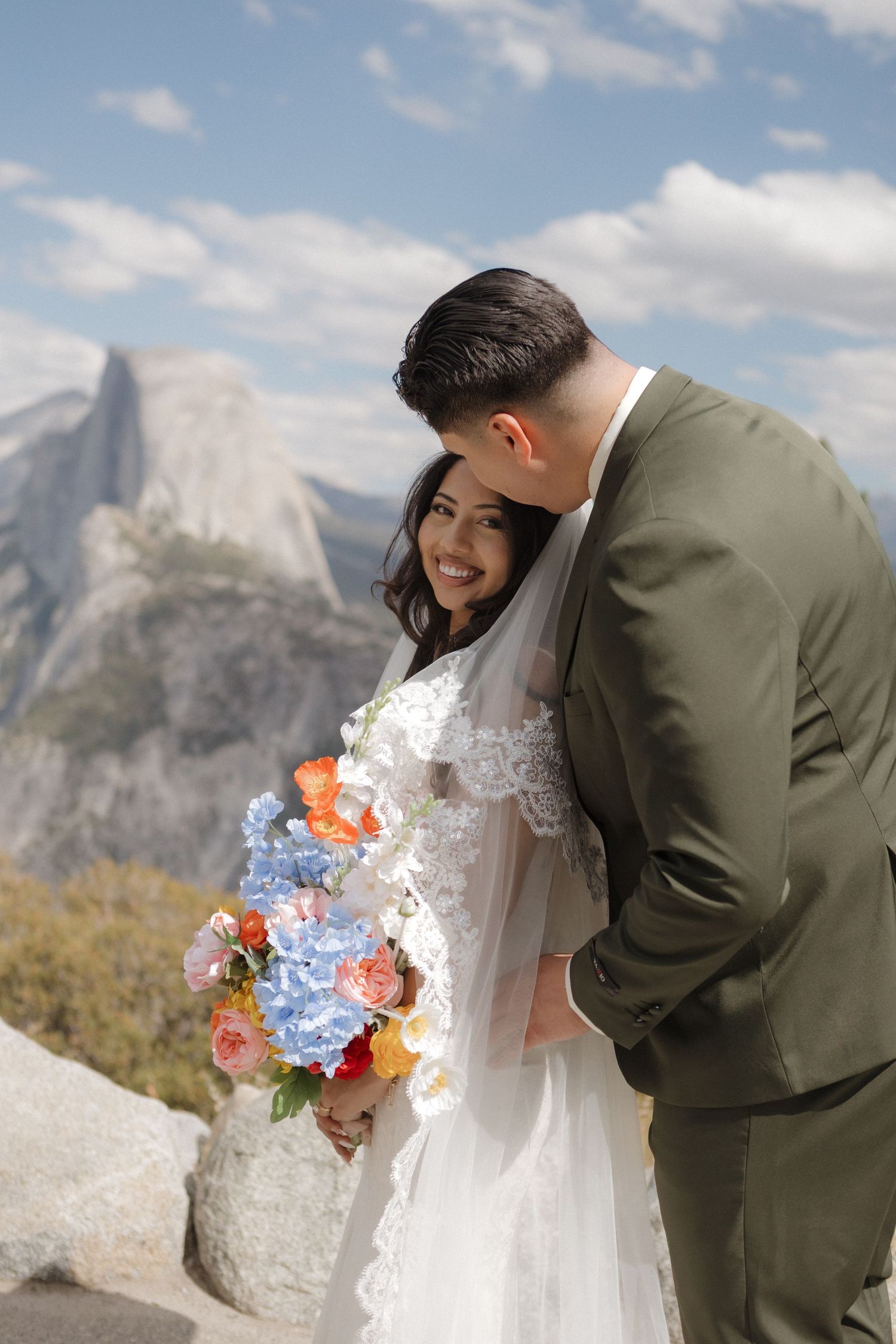 A couple shares a moment against dramatic mountain peaks at Yosemite.