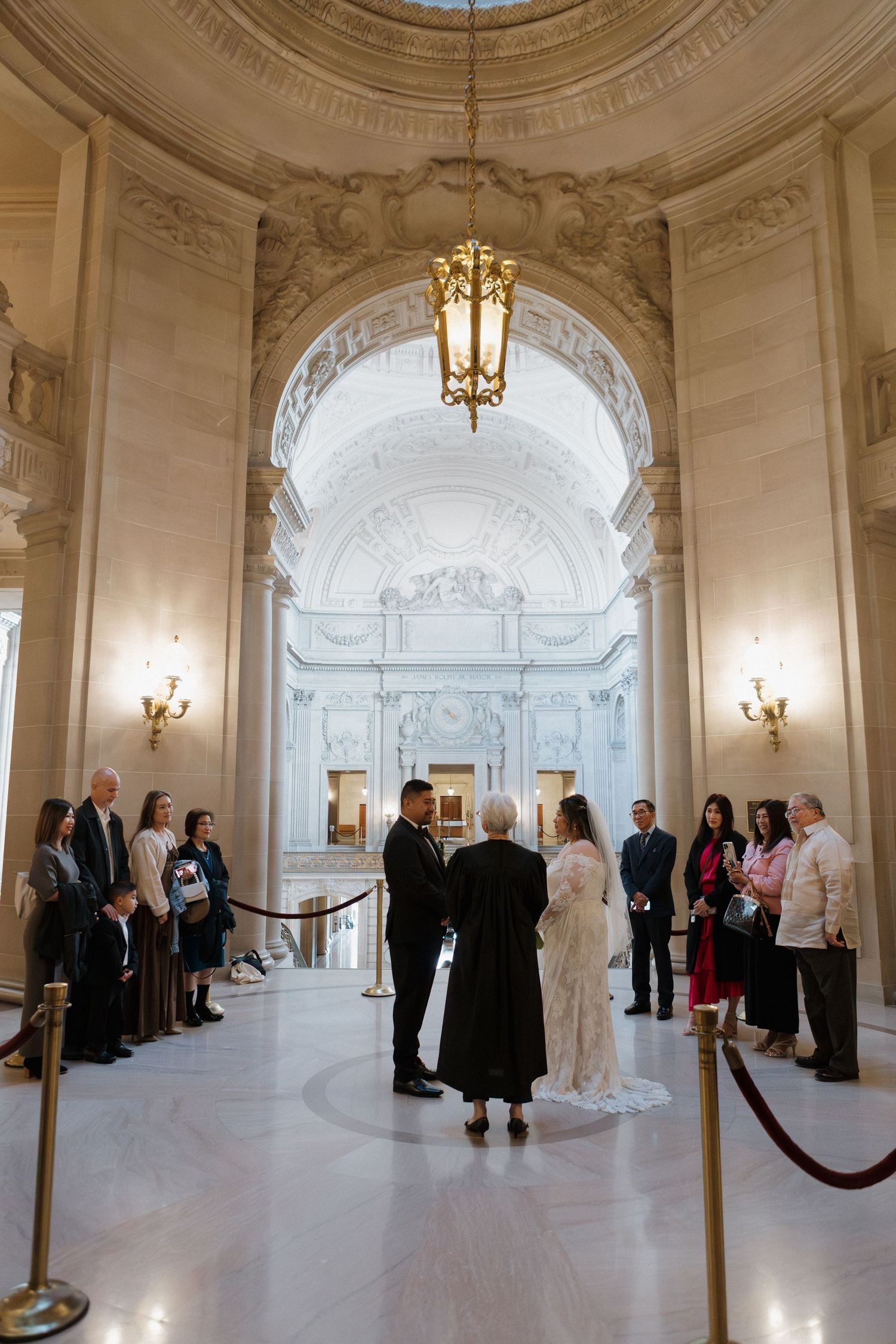 Panoramic view of an elegant white marble hall with guests gathered for a formal event.