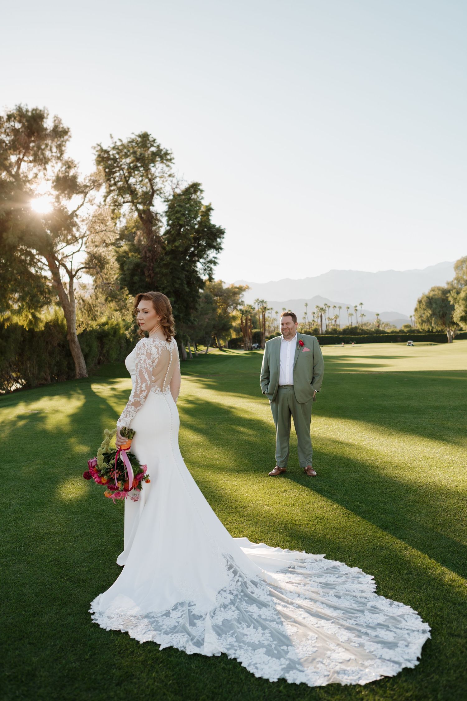 A stunning bridal portrait on a golf course showing the intricate lace train of the wedding dress.