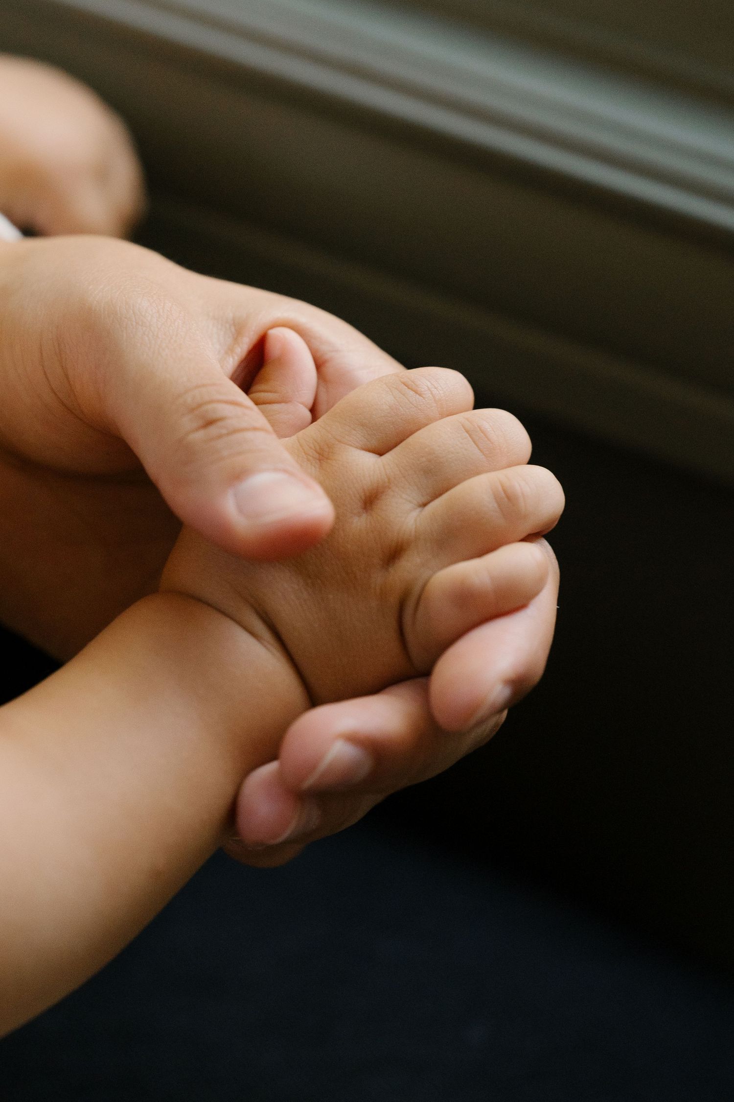 Close-up of an adult hand gently holding a small baby's hand, symbolizing love and parental bond.