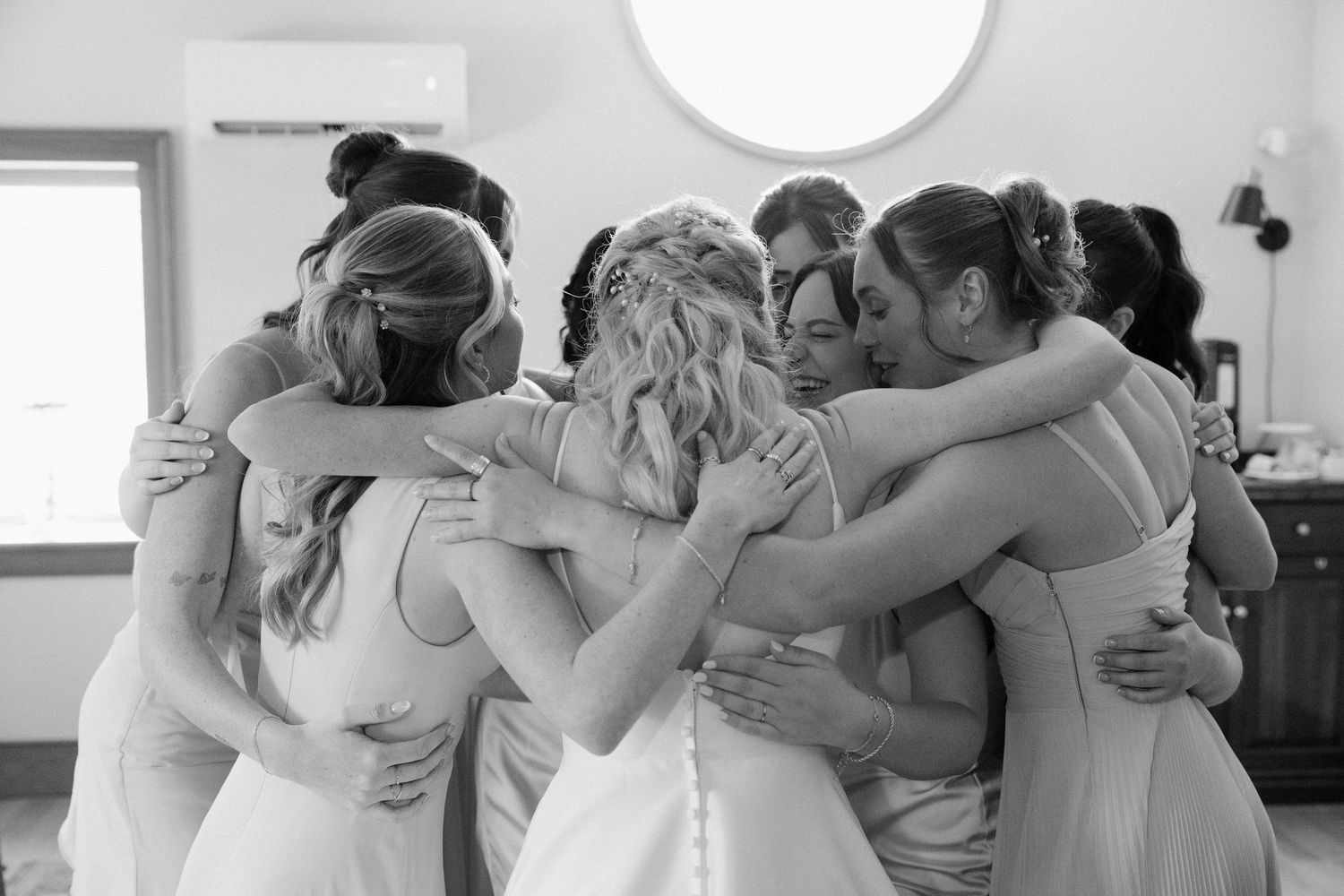 Bride and bridesmaids share an emotional group hug before the wedding ceremony.
