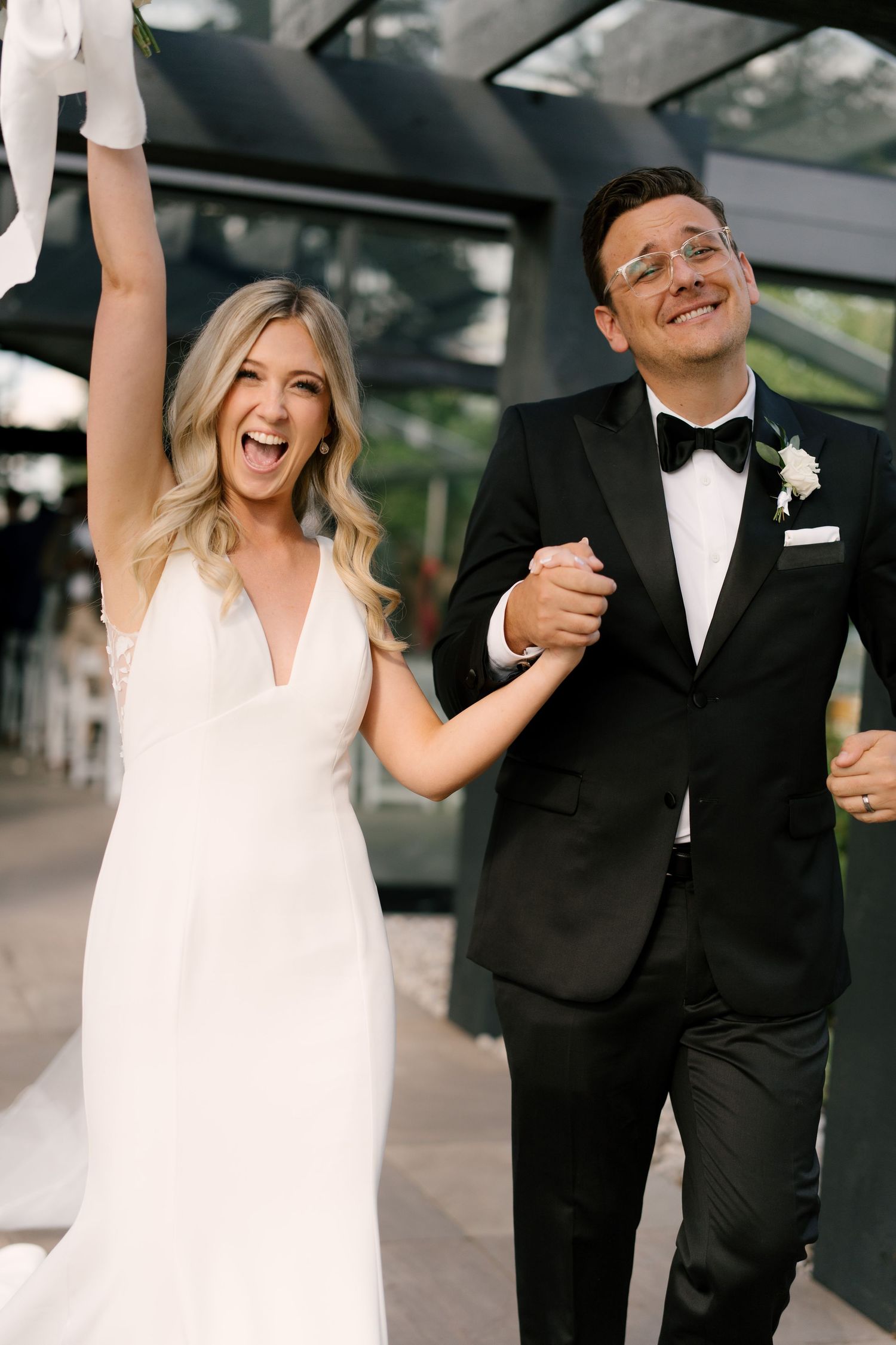 Joyful bride and groom in tuxedo celebrating after wedding ceremony with hands raised at Whistle Bear venue.