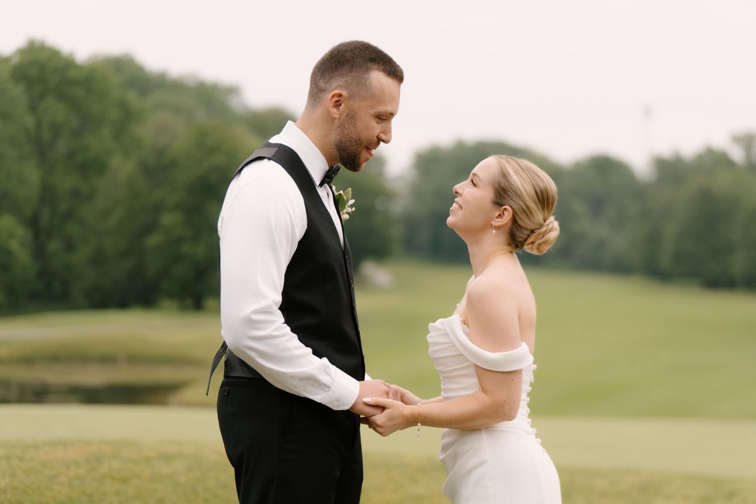 Smiling bride and groom holding hands on lush green golf course after ceremony.