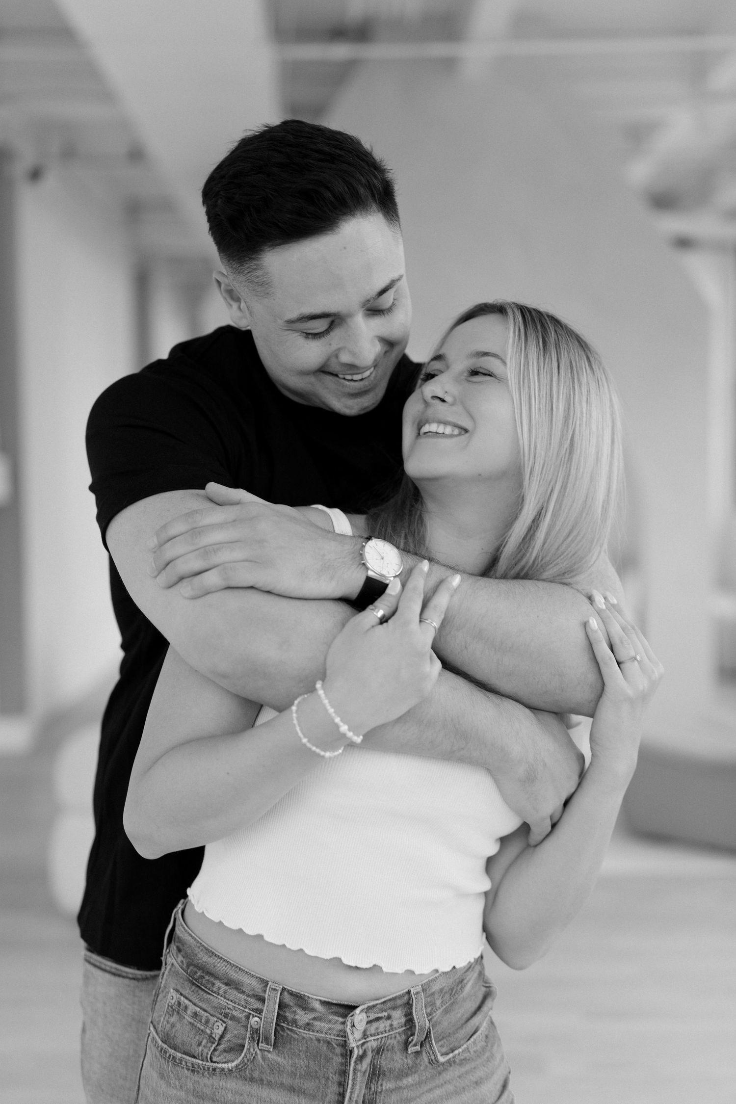 Black and white portrait of happy couple hugging, man wrapping arms around smiling blonde woman.