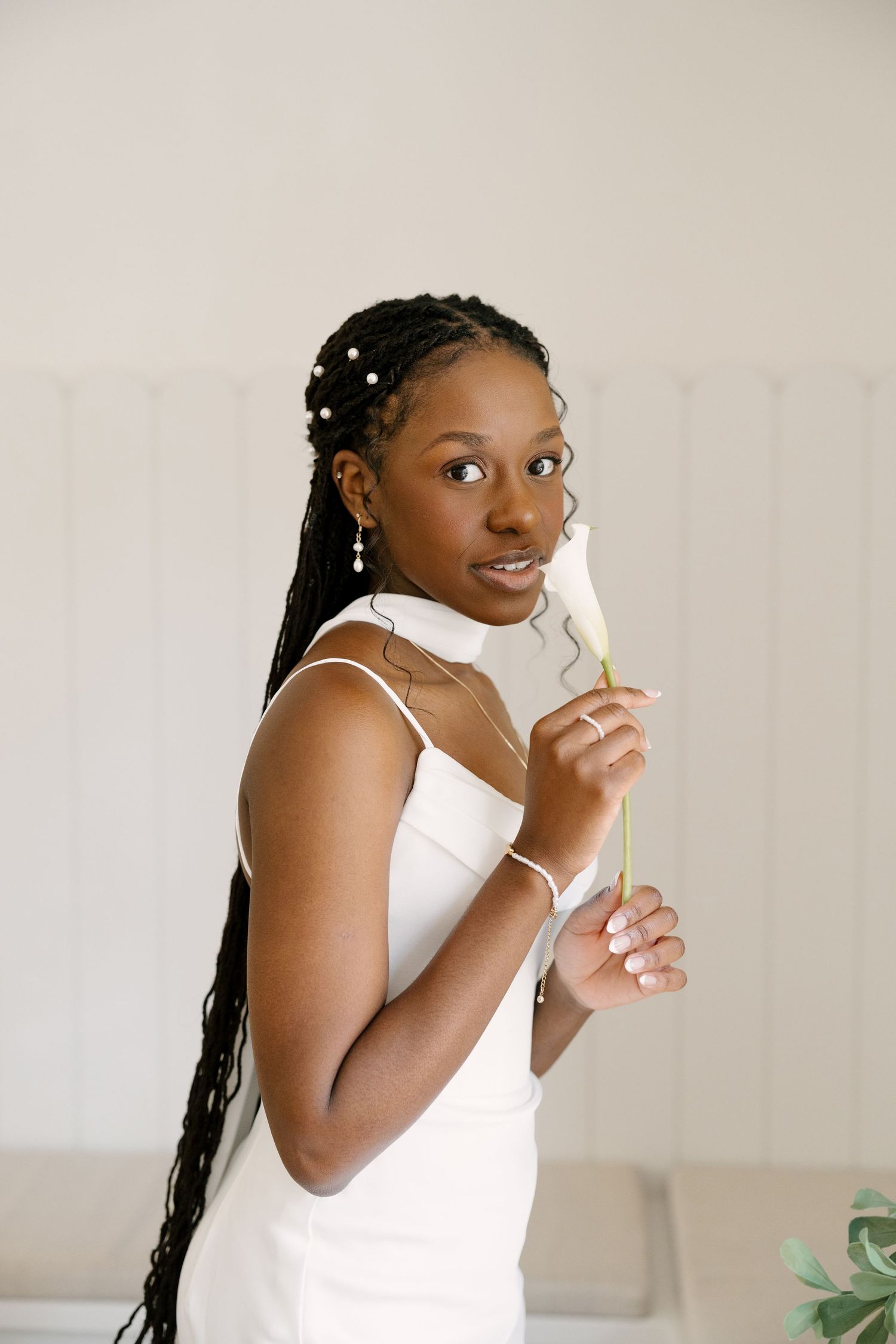 Elegant Black bride in white gown holding a white calla lily in a bright minimalist setting at Wren House.