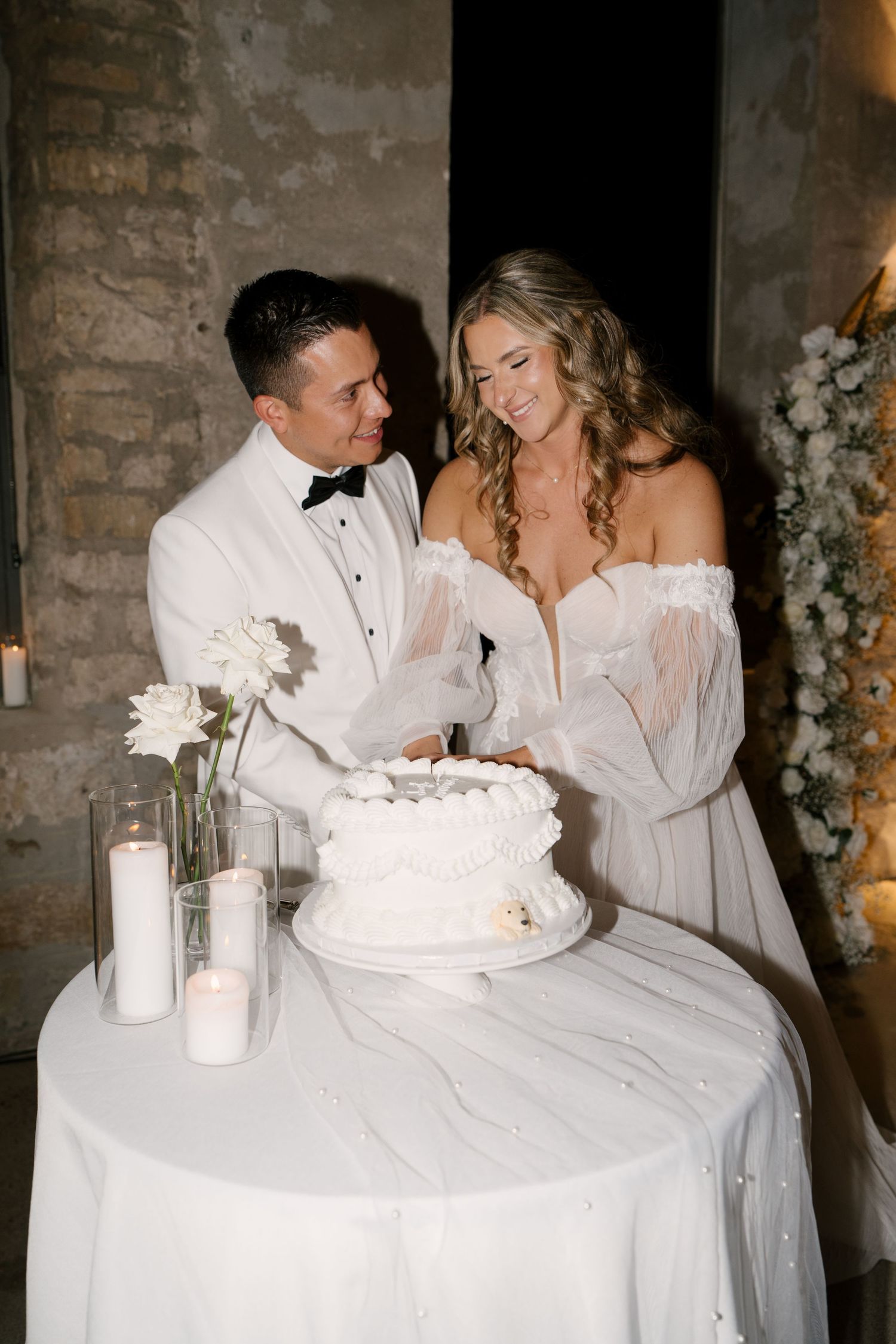 Bride and groom smiling while cutting their white wedding cake at Tapestry Hall reception.
