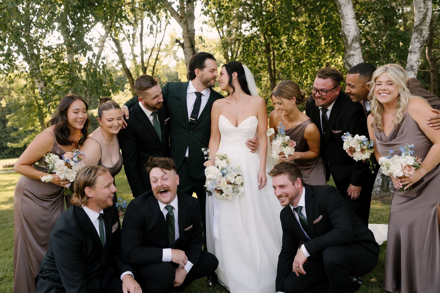 Joyful wedding party group photo with bride and groom surrounded by bridesmaids and groomsmen at Roseville Estates wedding venue.