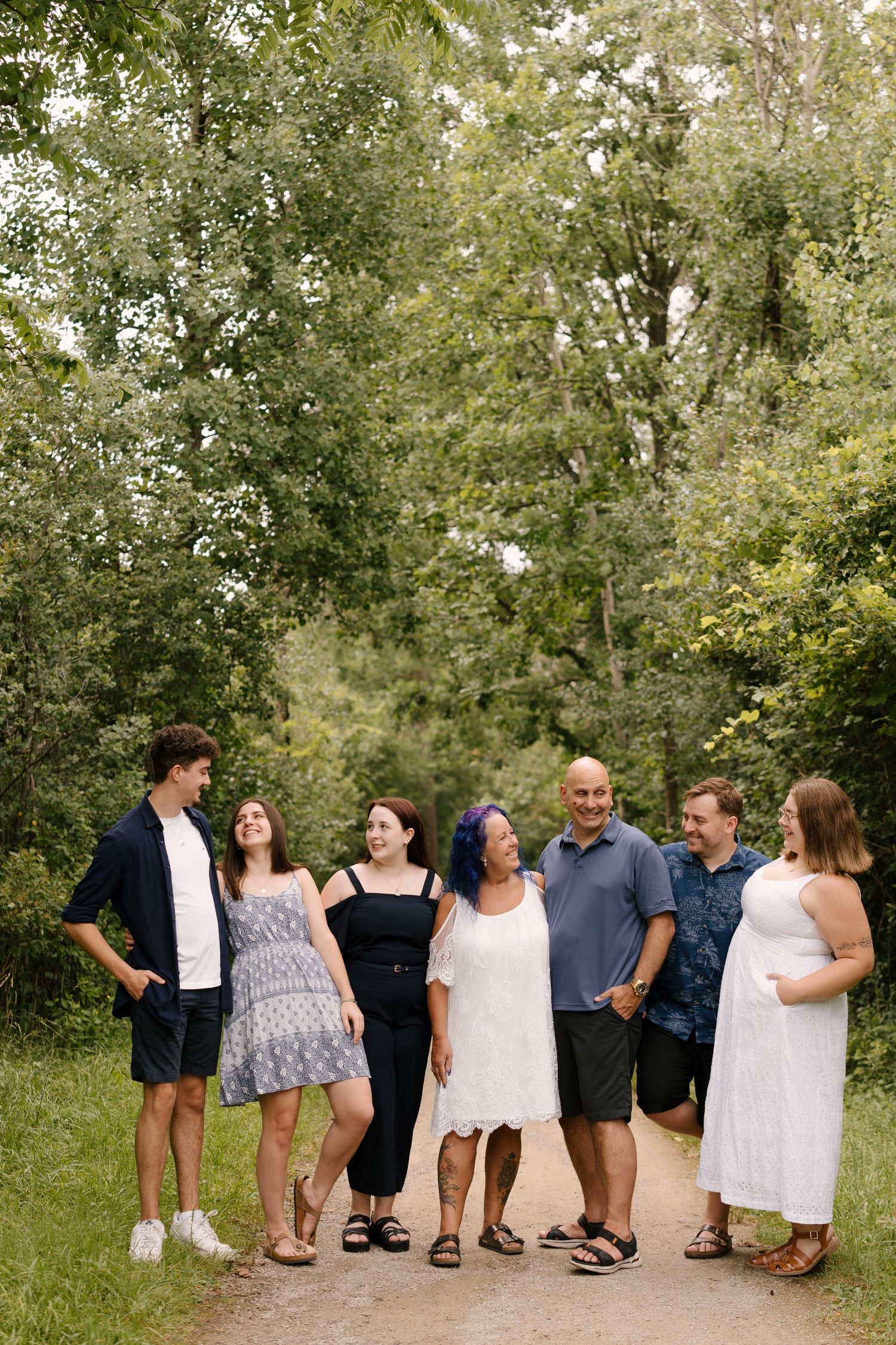 Extended family of seven laughing and enjoying an outdoor photo session on a dirt path.