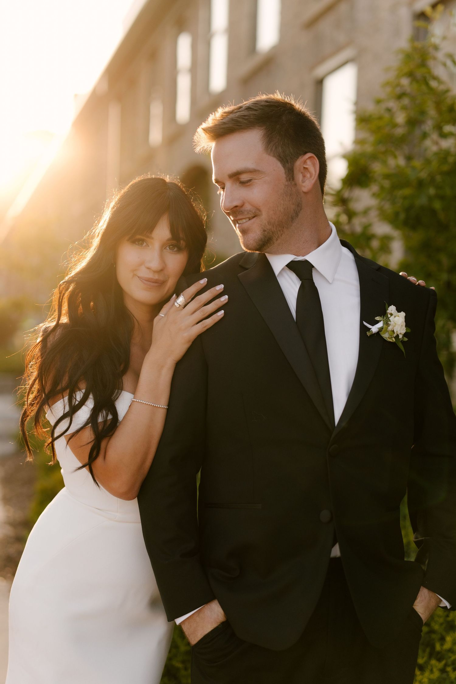 Bride and groom share a romantic golden hour moment outside a stone building at sunset at Tapestry Hall.