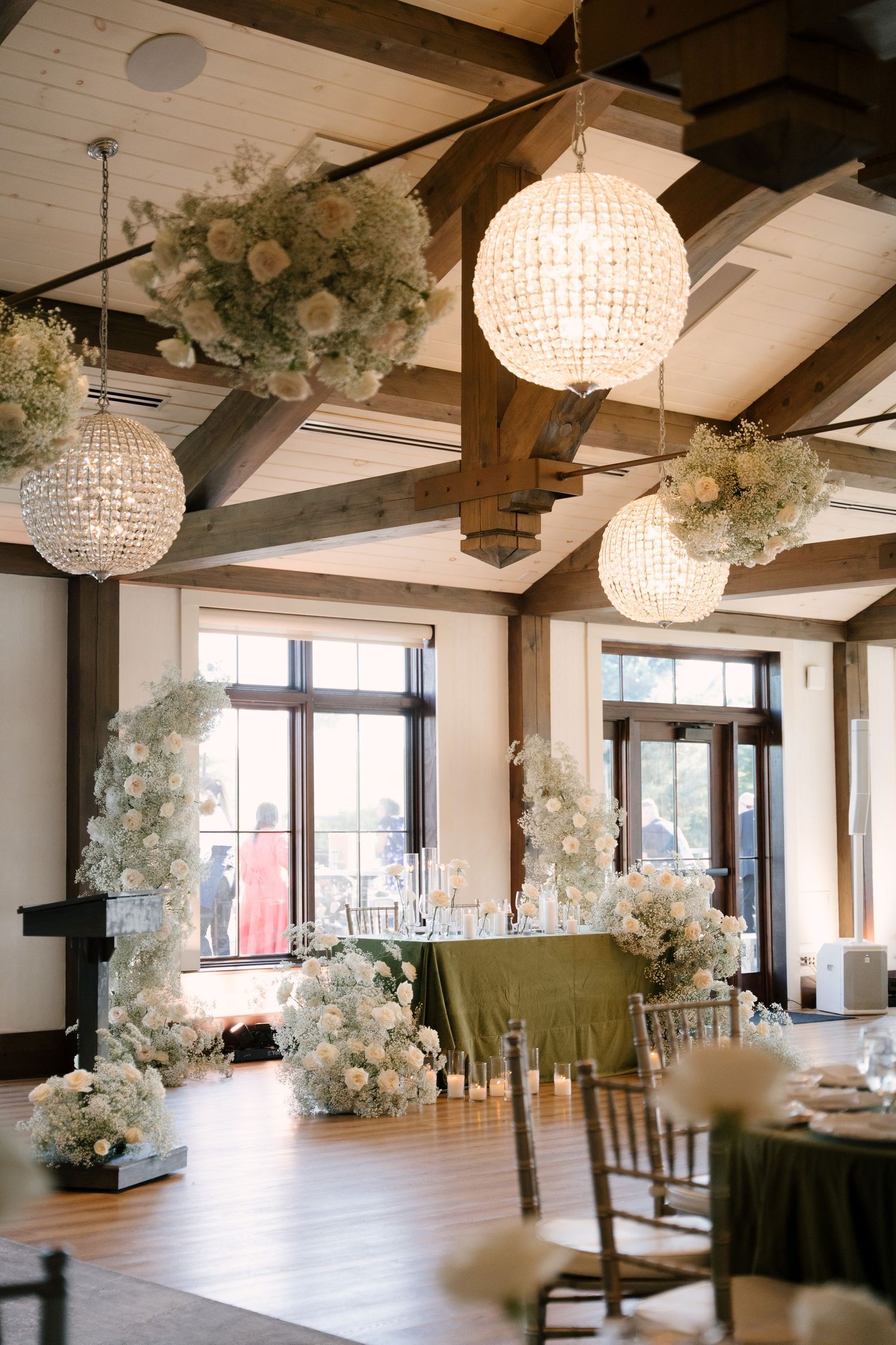 Romantic wedding reception at Whistle Bear venue with floral installations and crystal chandeliers above head table.