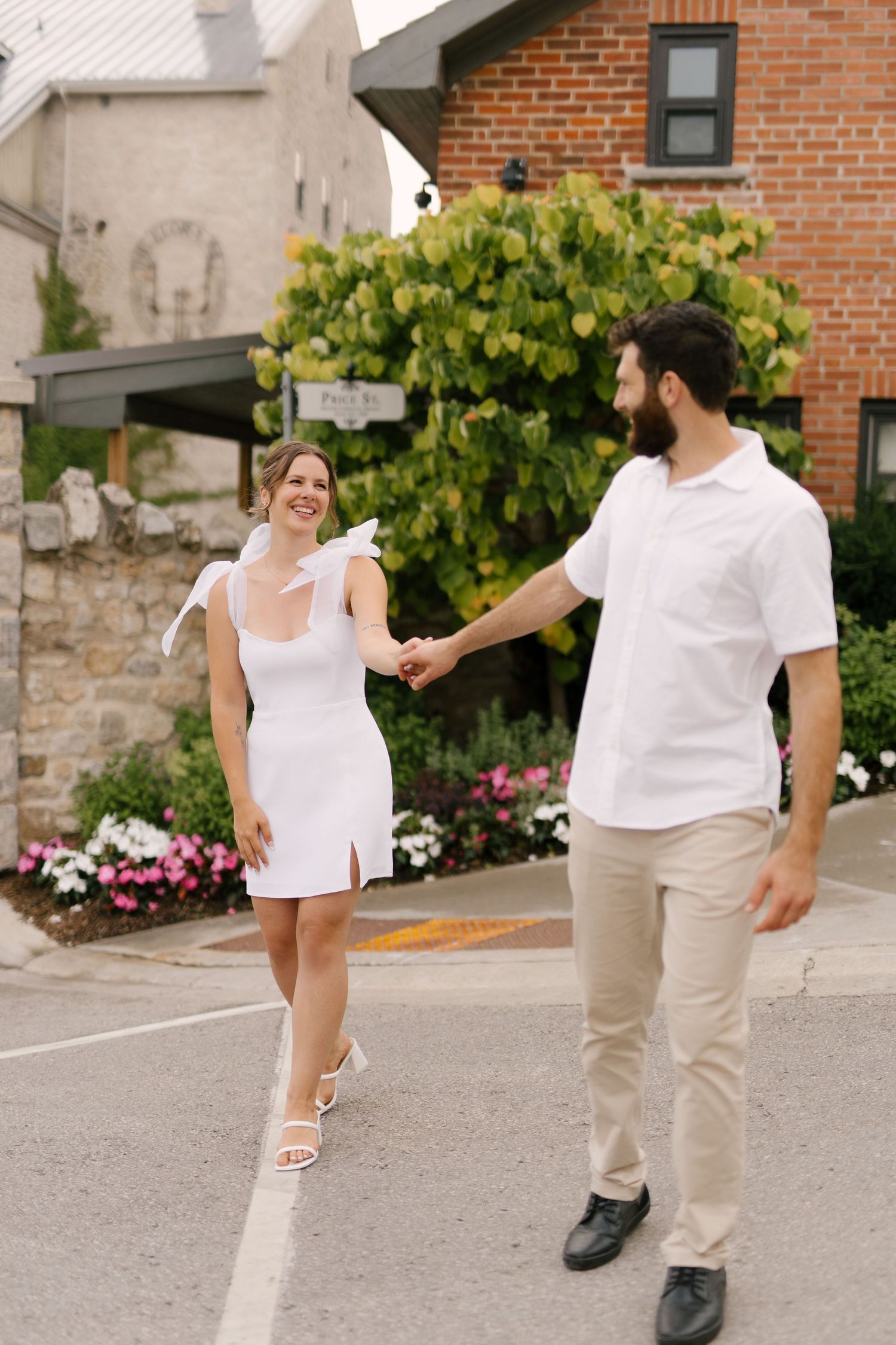 Happy couple holding hands and walking together on a street with flowers in background.