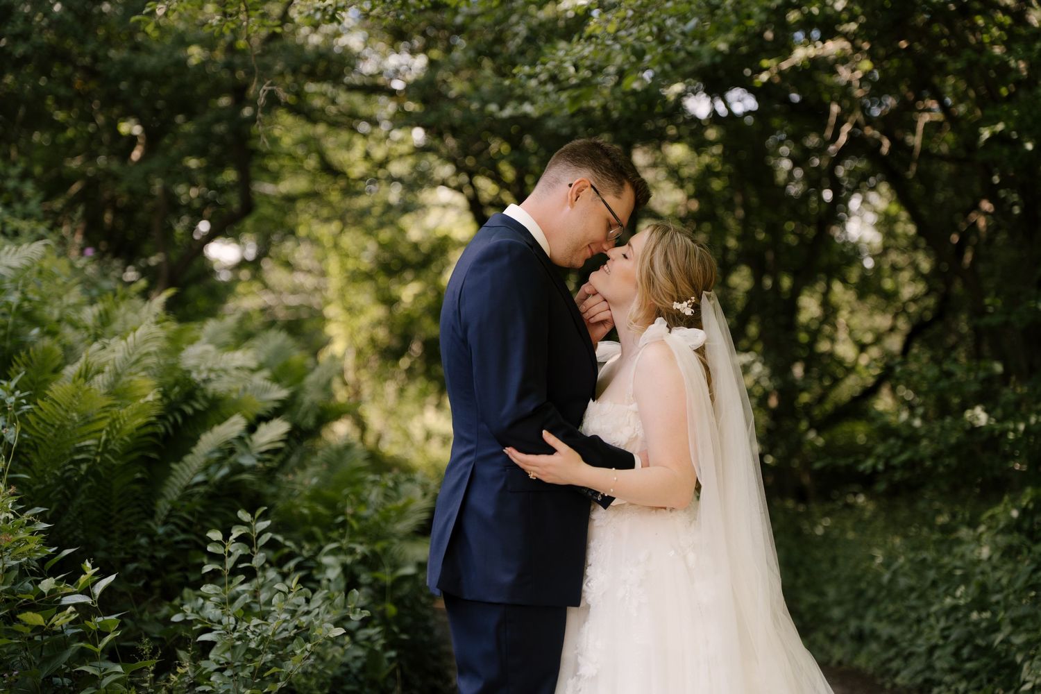 Bride and groom sharing tender forehead touch moment surrounded by lush green garden foliage at St Marys Golf Club.