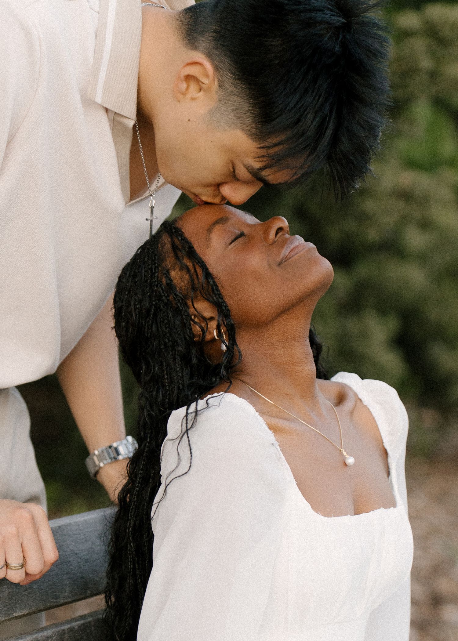Man tenderly kissing woman on forehead as she tilts head back with eyes closed.