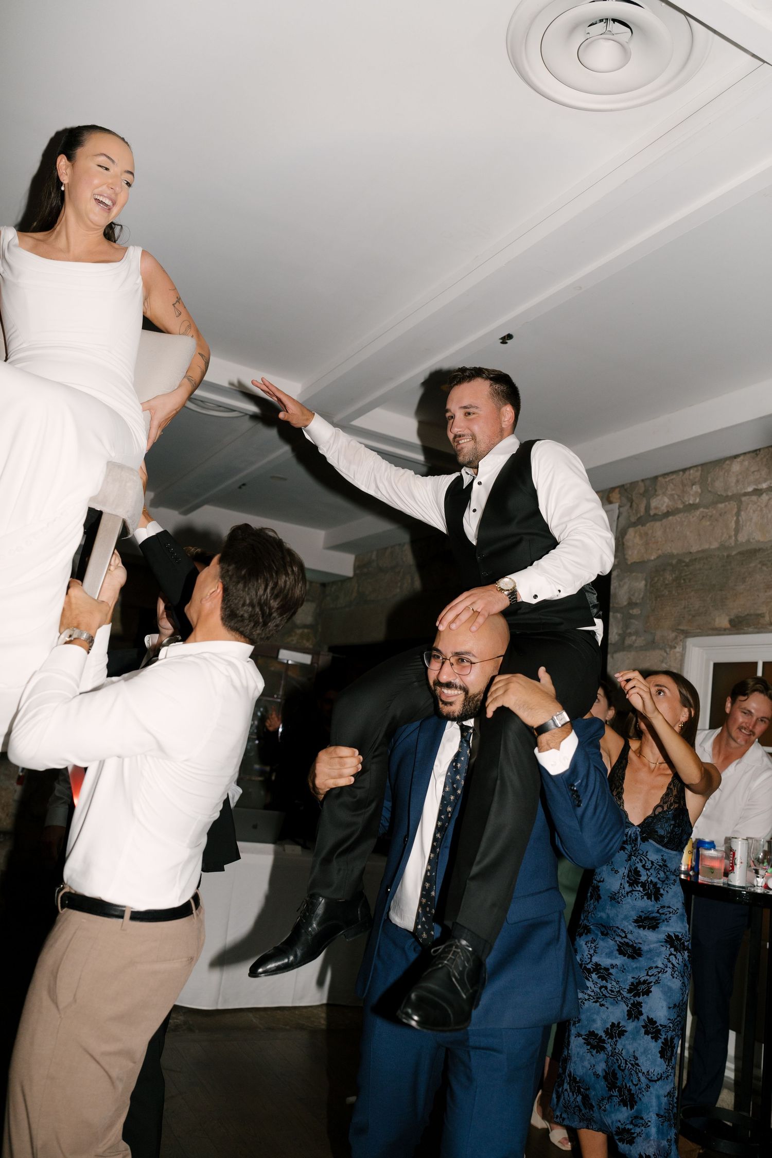 Bride and groom lifted on shoulders by guests during joyful wedding reception dance at Cambridge Mill.