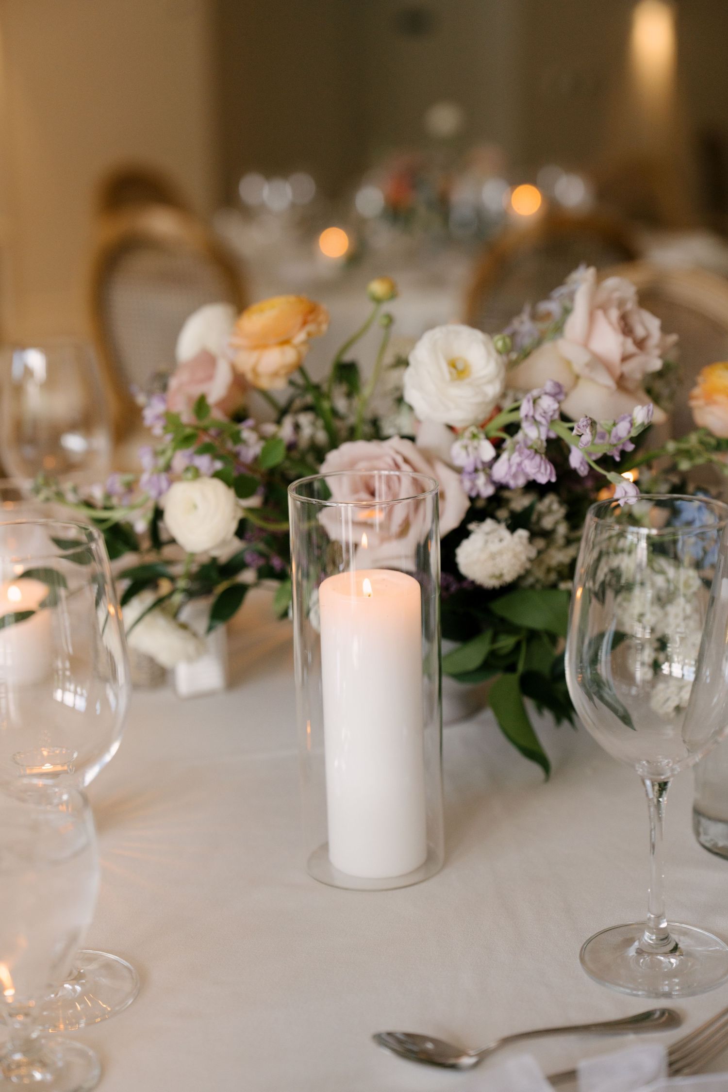 Elegant wedding table centrepiece with pillar candle, blush roses, and lavender blooms at Roseville Estates wedding venue.