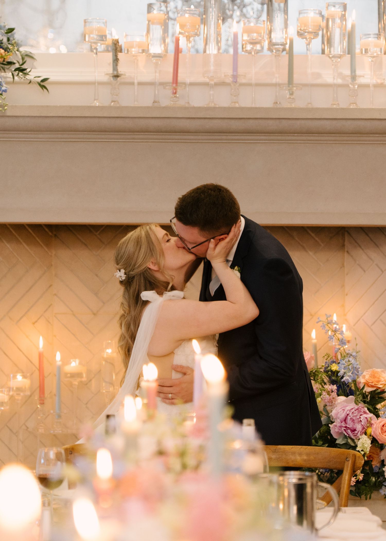 Bride and groom sharing first kiss at candlelit reception table with floral centrepieces at St Marys Golf Club.