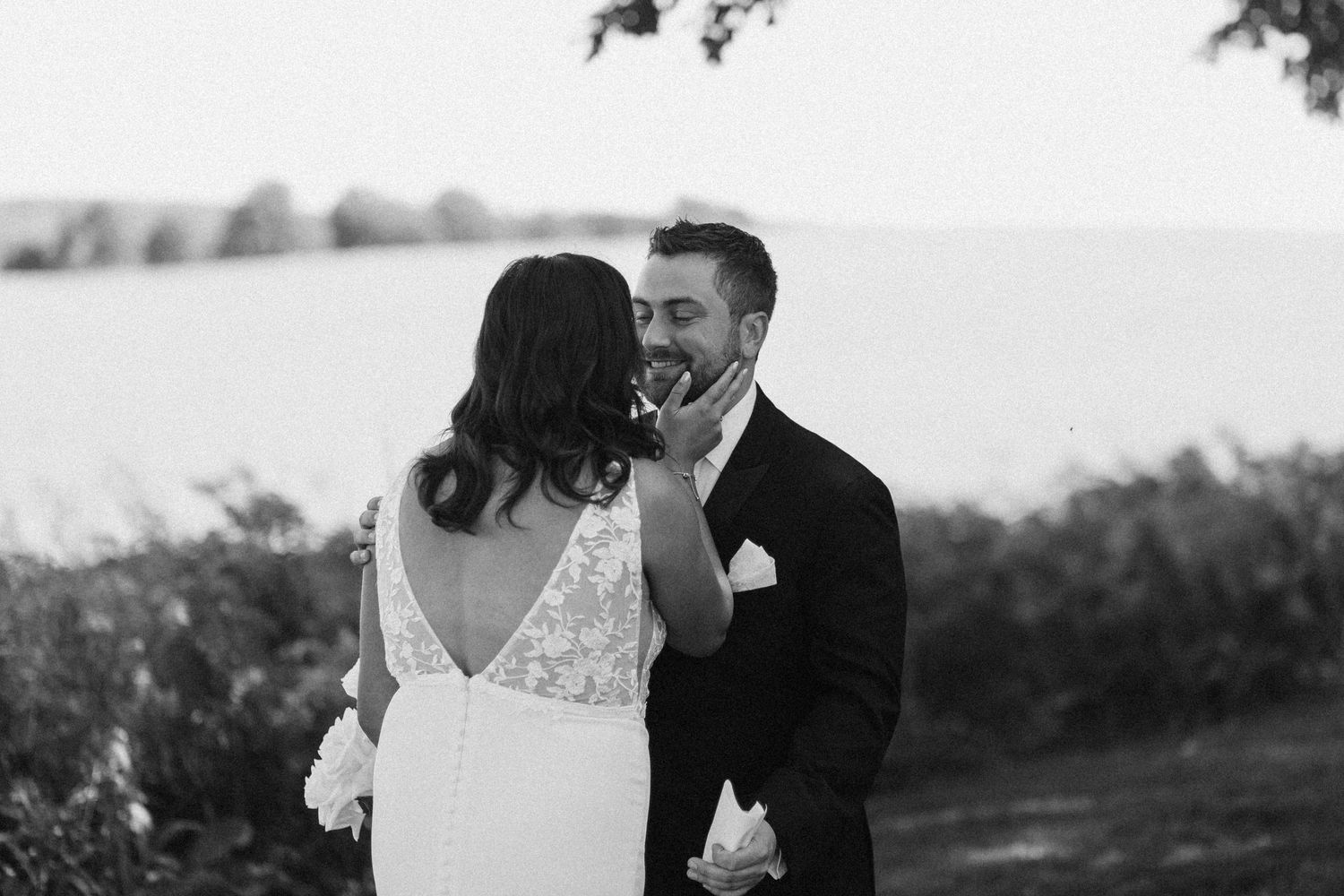Black and white photo of smiling groom gazing at bride near a garden at Wakefield Estates.