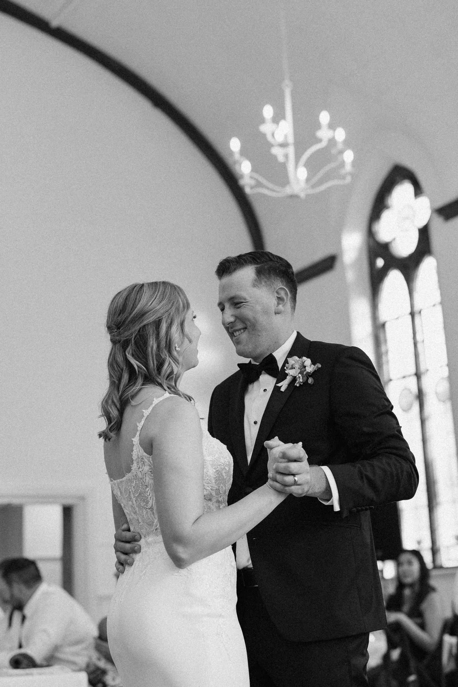 Black and white photo of bride and groom sharing their first dance in an elegant church venue.