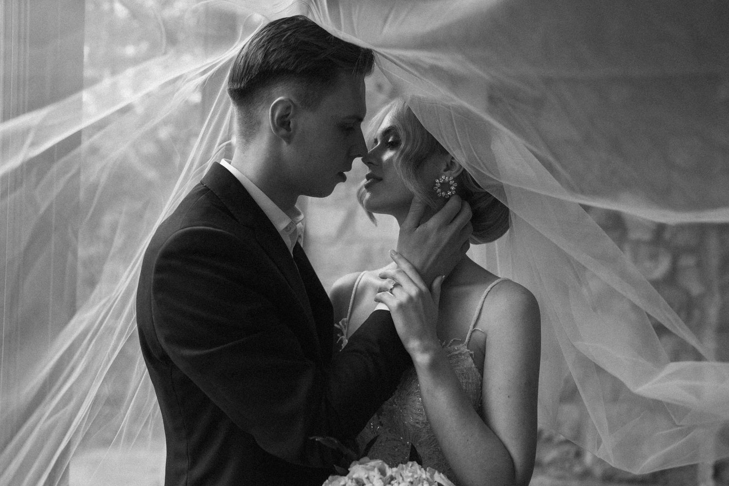 Black and white photo of bride and groom almost kissing under a flowing wedding veil at Cambridge Mill.