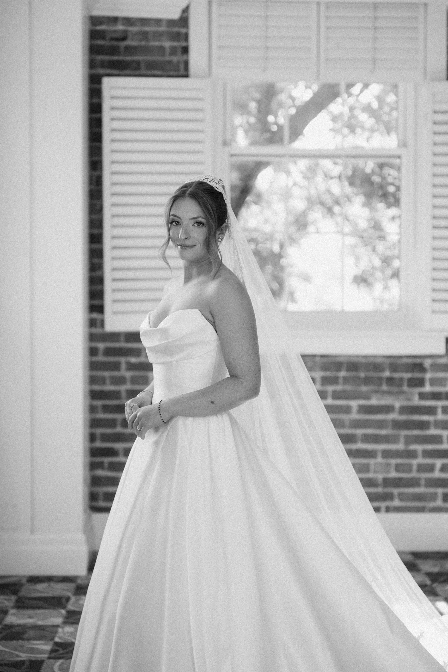 Elegant bride in strapless ball gown and veil posing in black and white portrait at Pillar and Post.