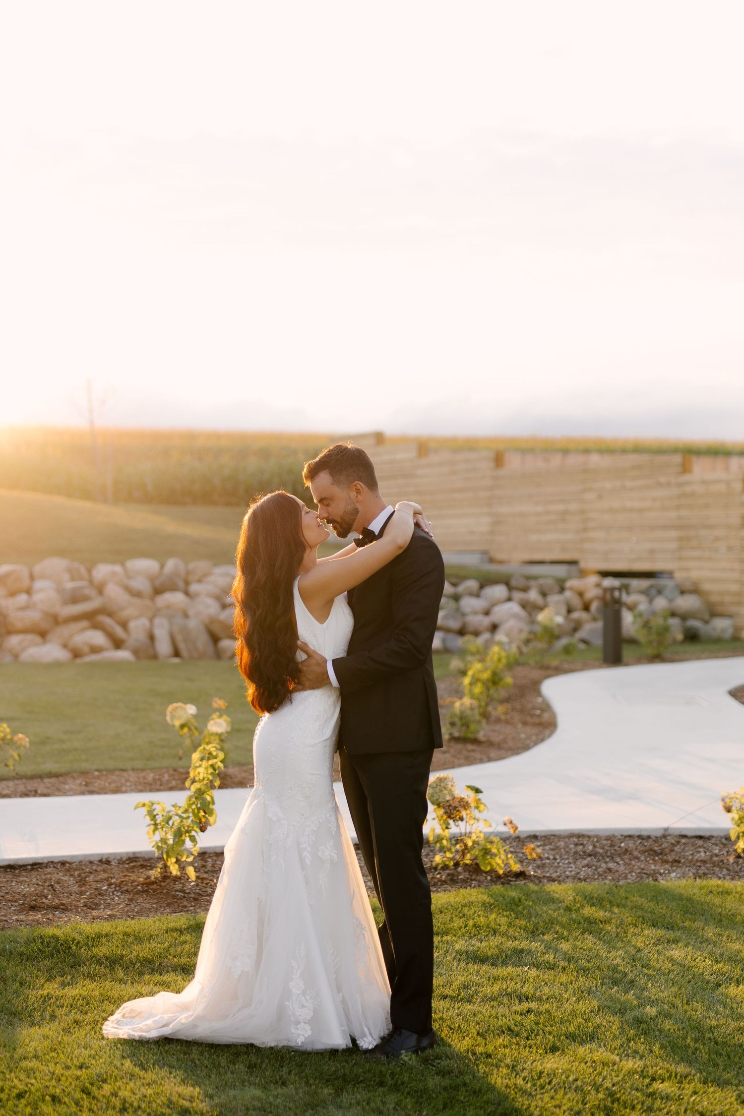 Bride and groom sharing a tender moment at sunset in an elegant outdoor garden venue at Wakefield Estates.
