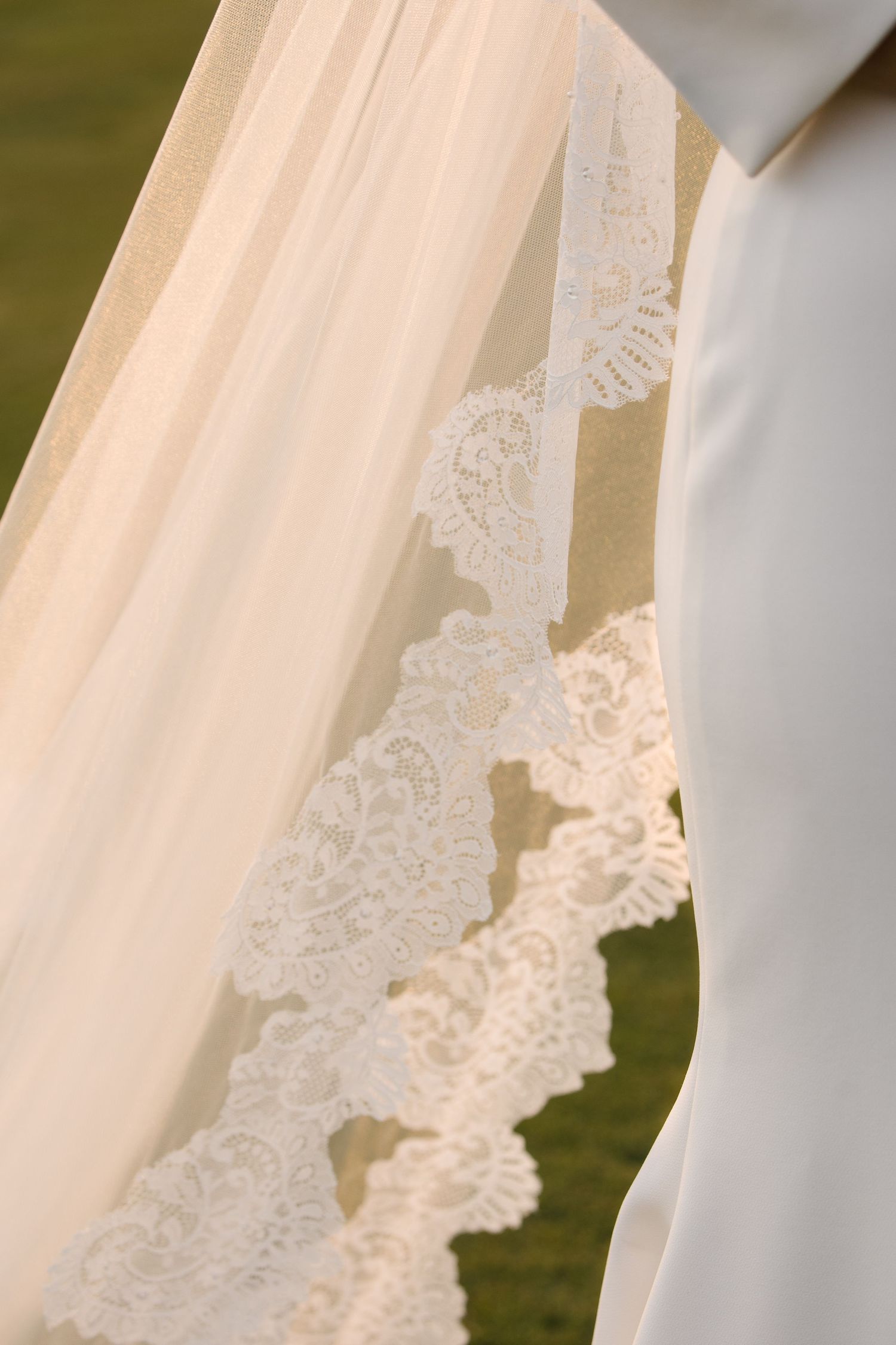 Close-up detail of elegant lace-trimmed cathedral wedding veil with intricate floral embroidery pattern.