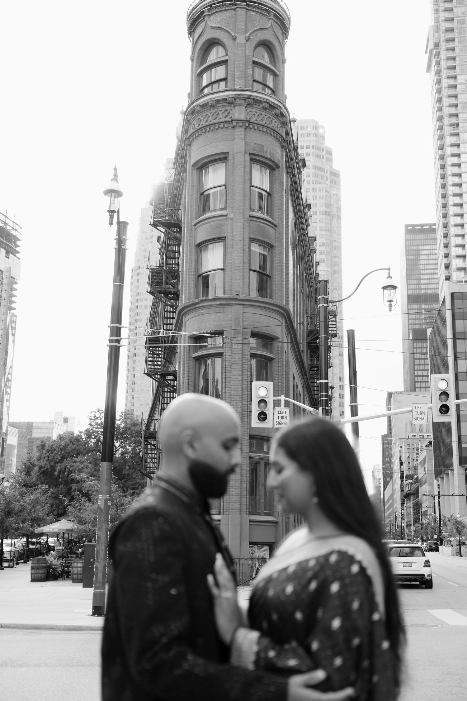 Black and white engagement photo of Indian couple with Toronto Gooderham Building backdrop.