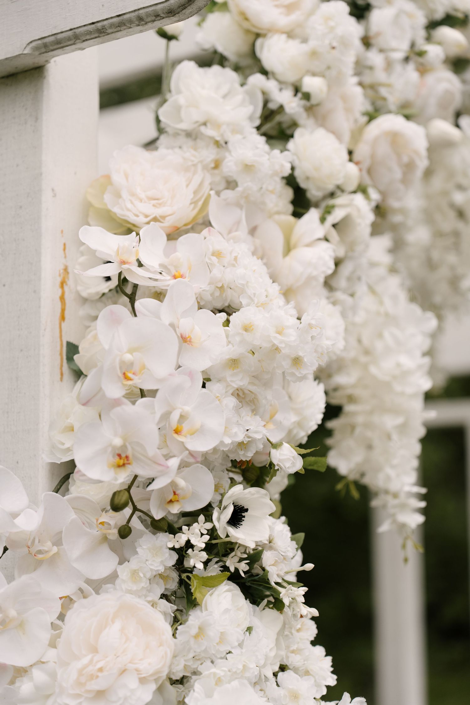 Lush wedding arch adorned with white roses, orchids, and delicate blooms for an elegant ceremony.