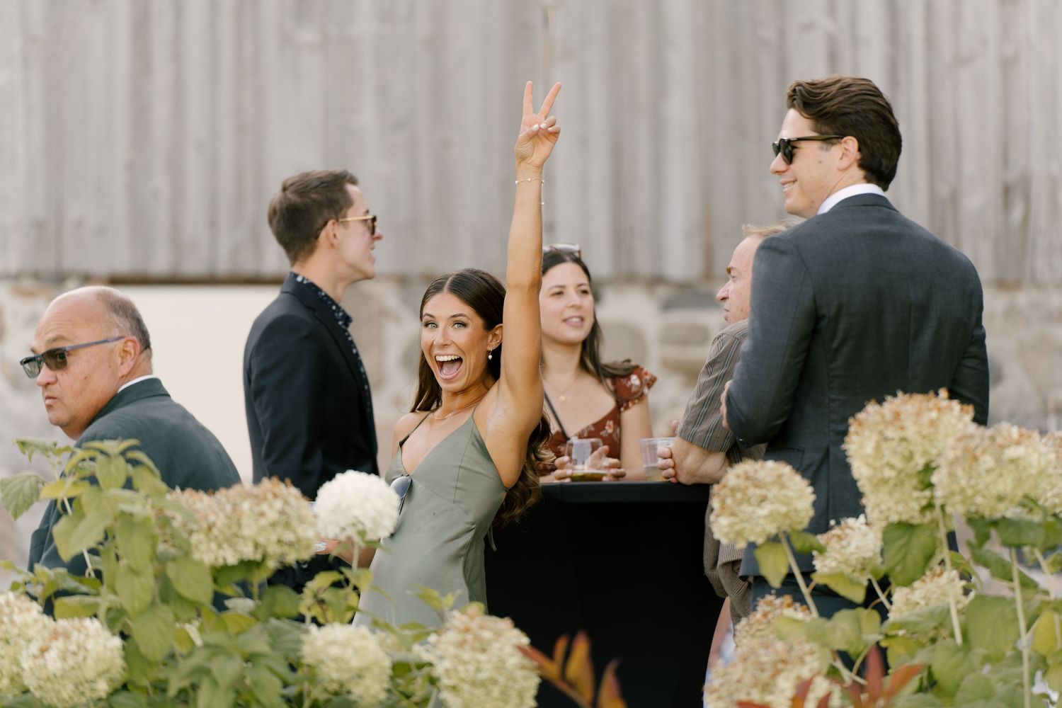Guests laughing and posing at an outdoor wedding reception surrounded by white hydrangeas at Wakefield Estates.