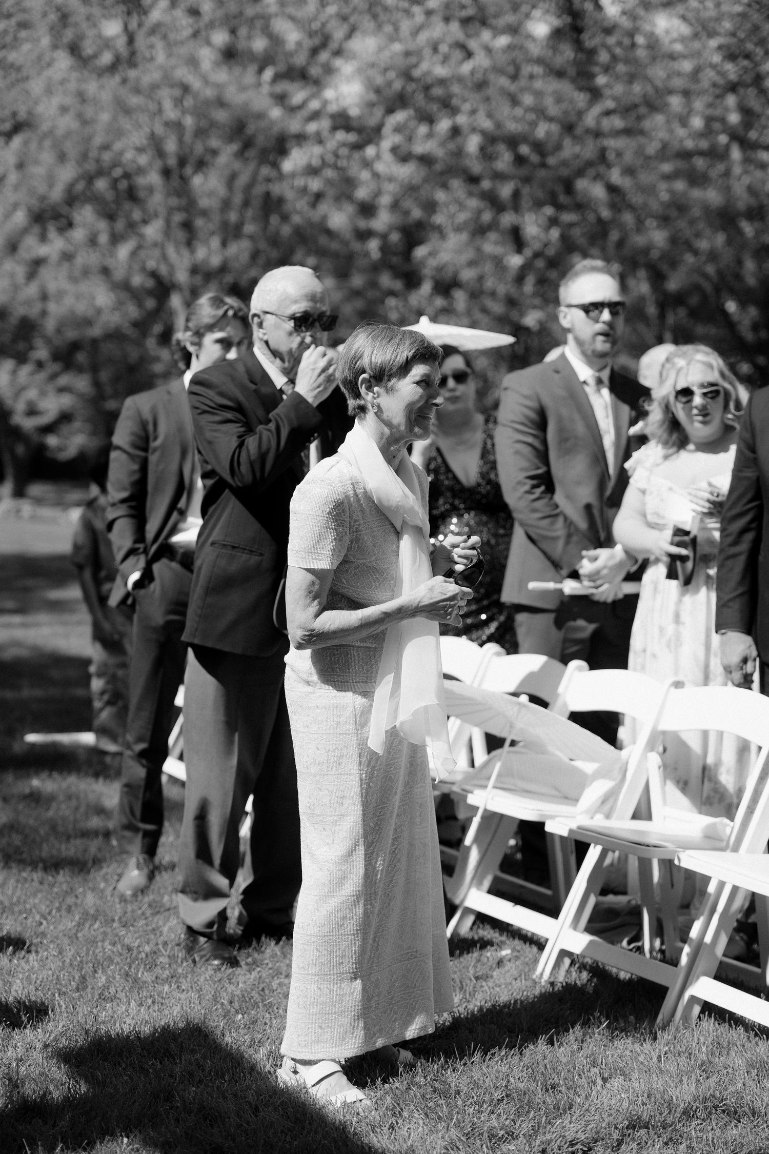 Emotional wedding guests embrace and wipe tears during an outdoor wedding ceremony at Roseville Estates.