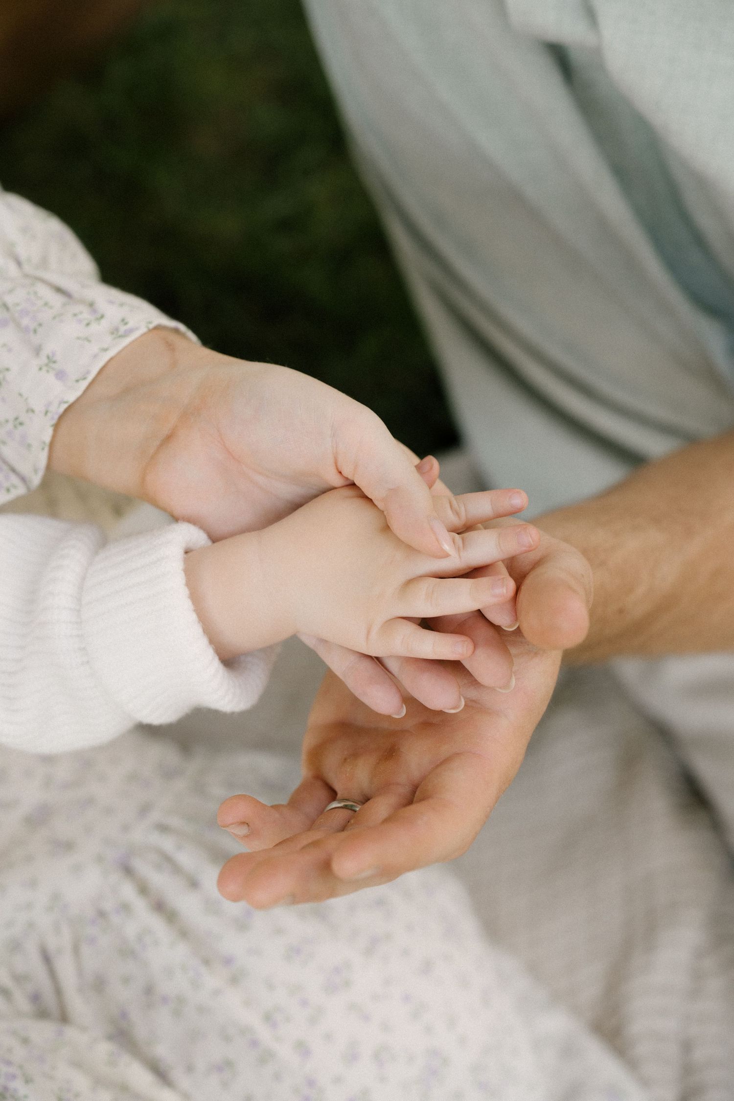 Close-up of mother, father, and baby hands touching gently together.