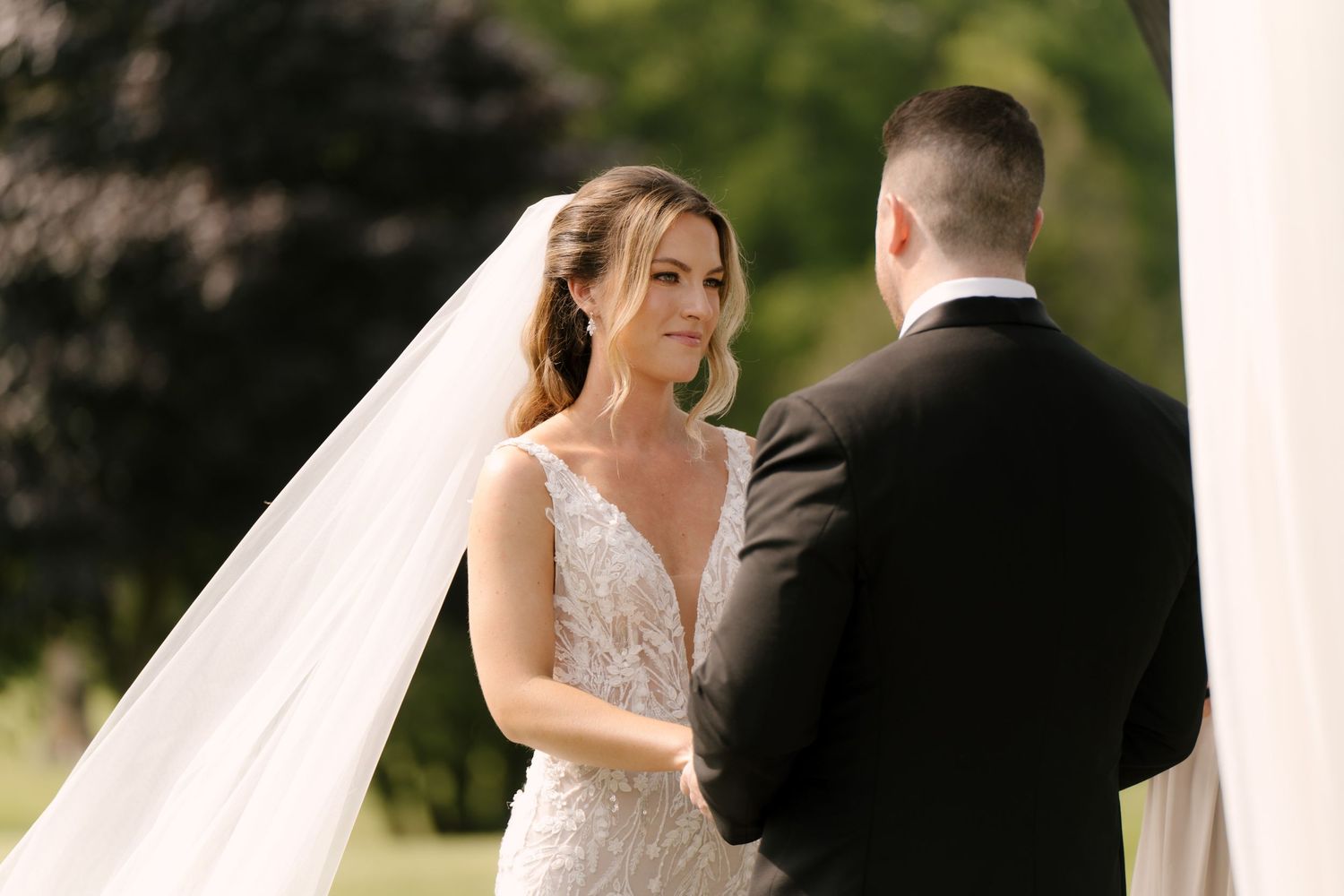 Bride in lace gown and veil exchanges vows with groom during an outdoor wedding ceremony at St Marys Golf Club.