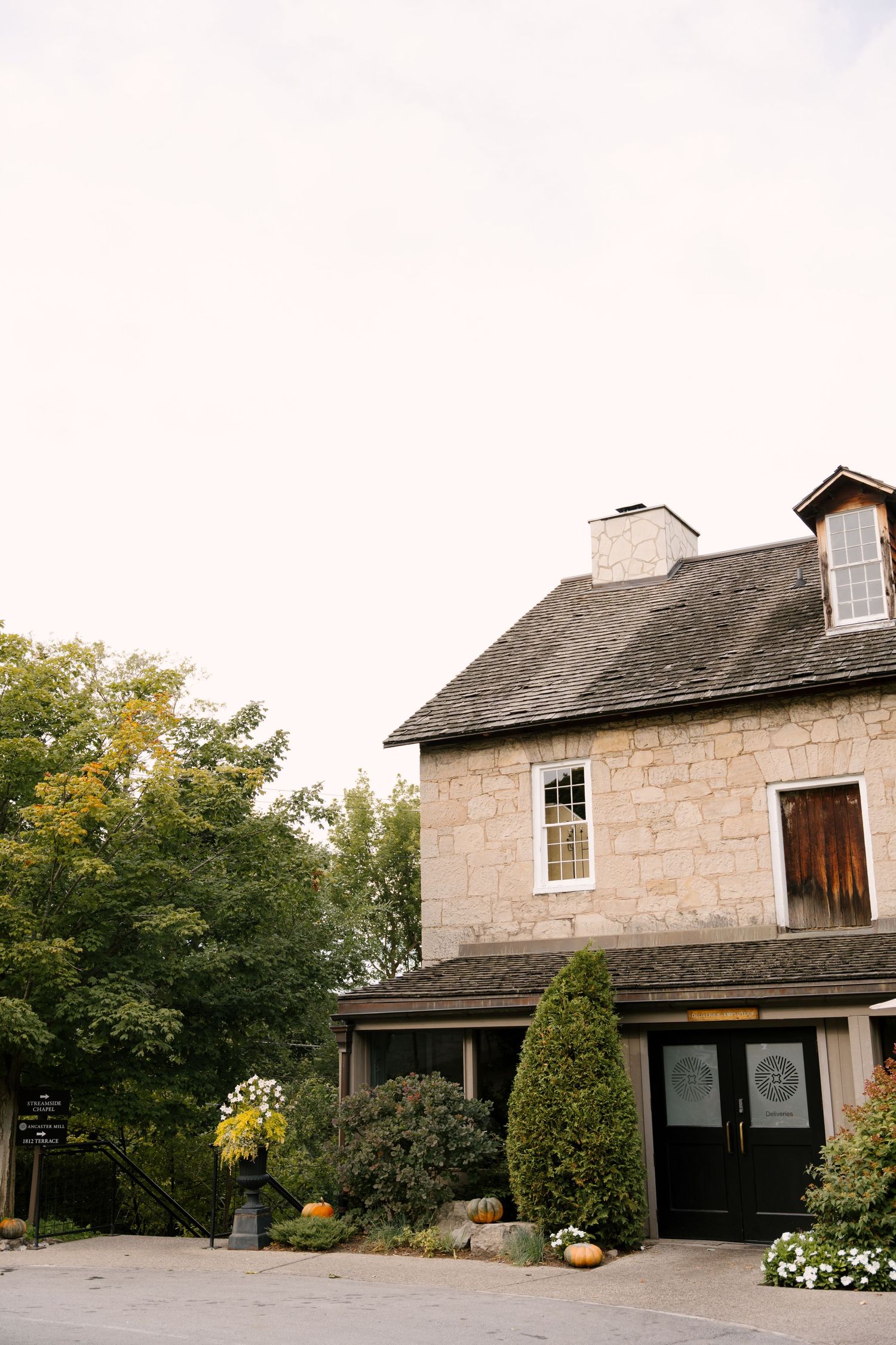 Rustic stone Ancaster Mill building wedding venue surrounded by autumn trees with elegant double door entrance.
