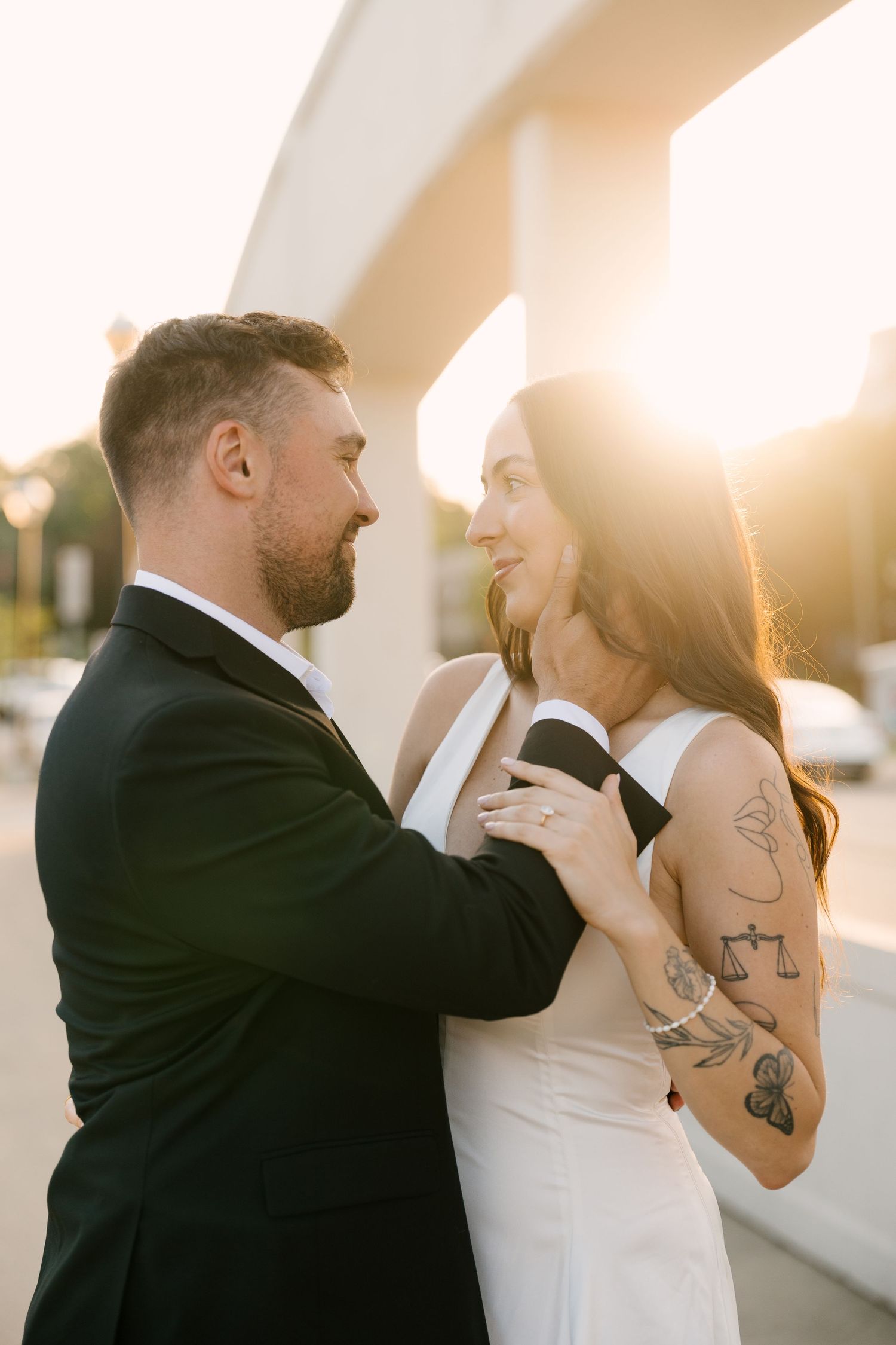 Bride and groom gazing at each other in golden hour light, bride's tattoos visible.