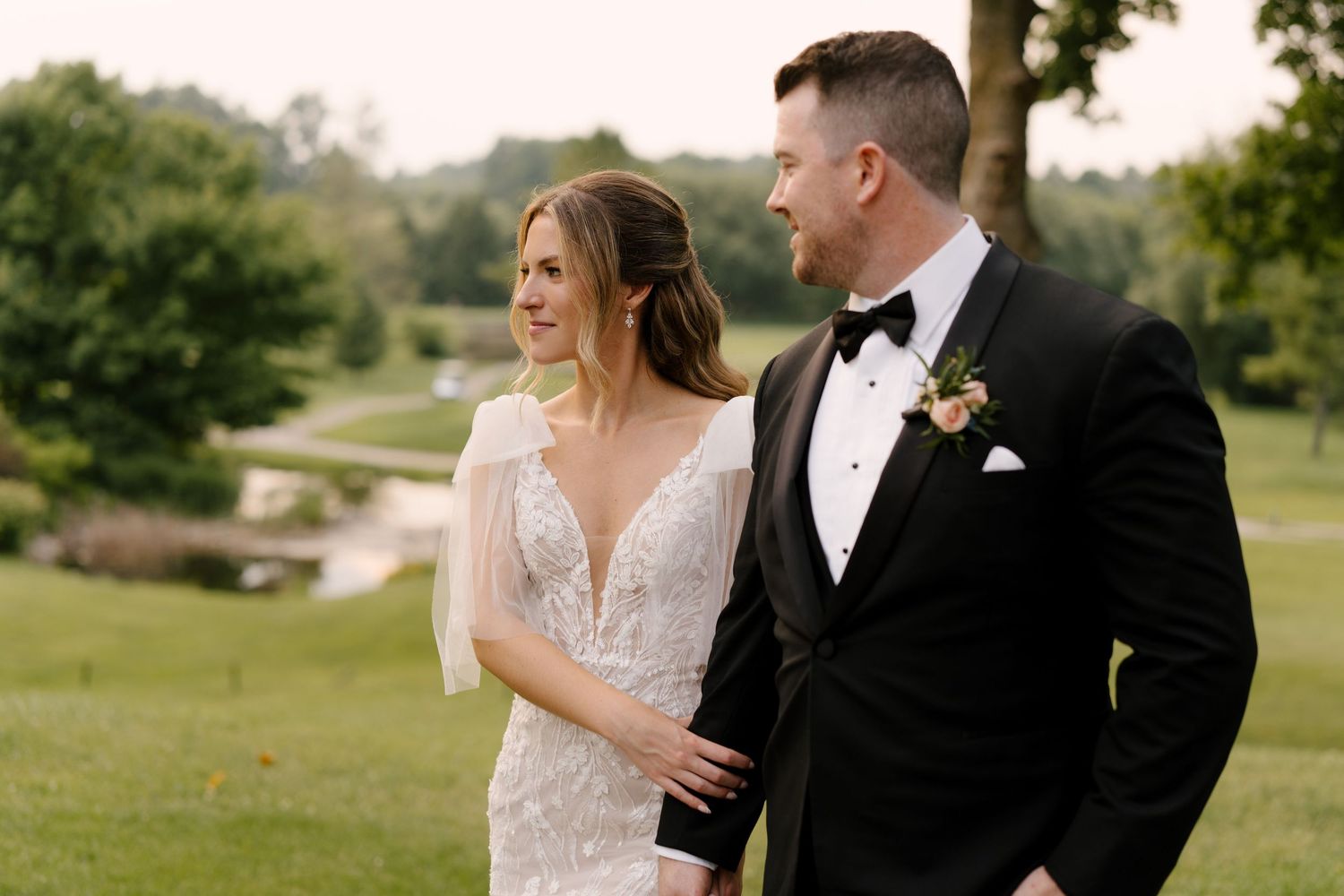 Bride in white lace gown and groom in black tuxedo sharing a tender moment on St Marys golf course.