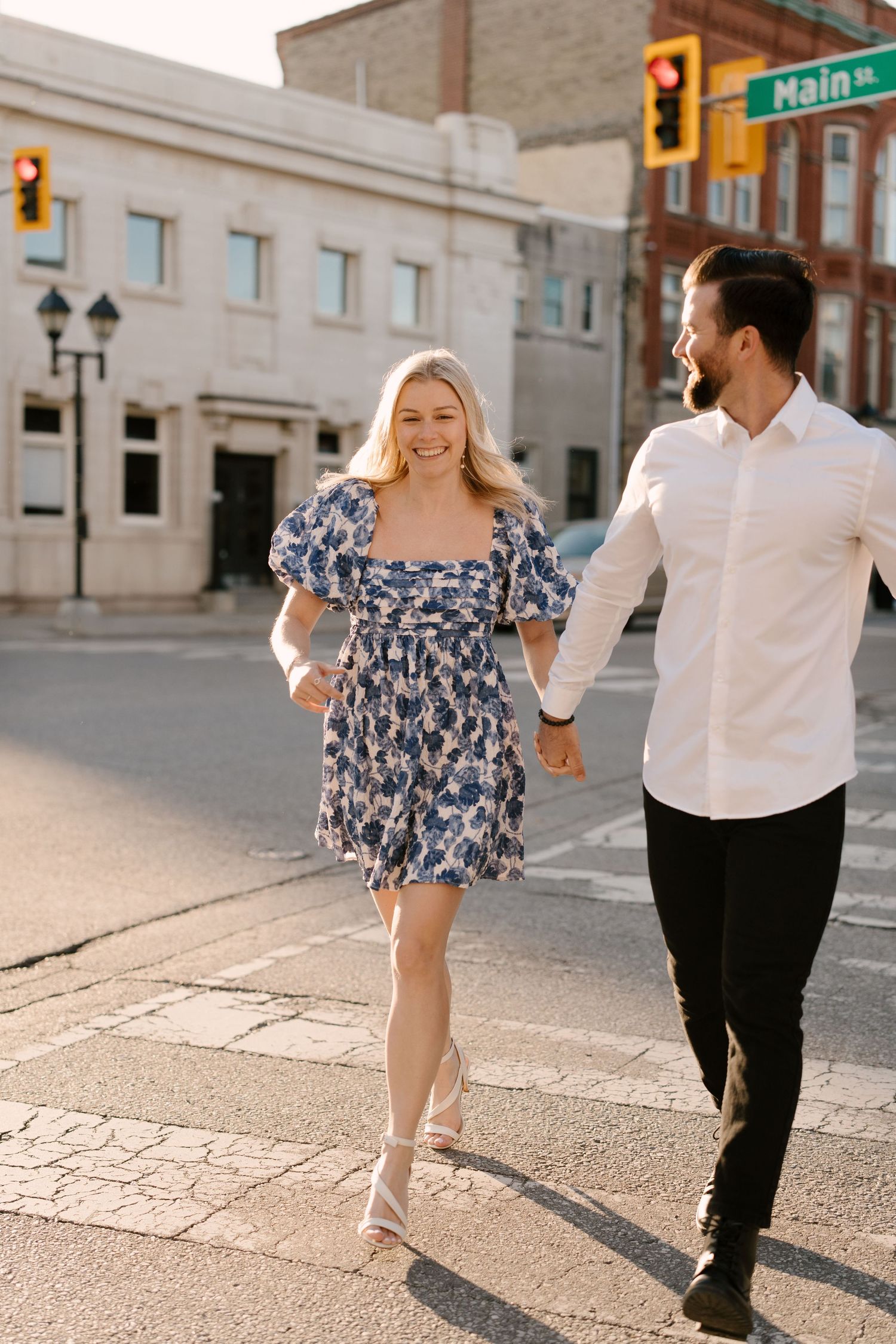 Smiling couple holding hands crossing Main Street intersection.