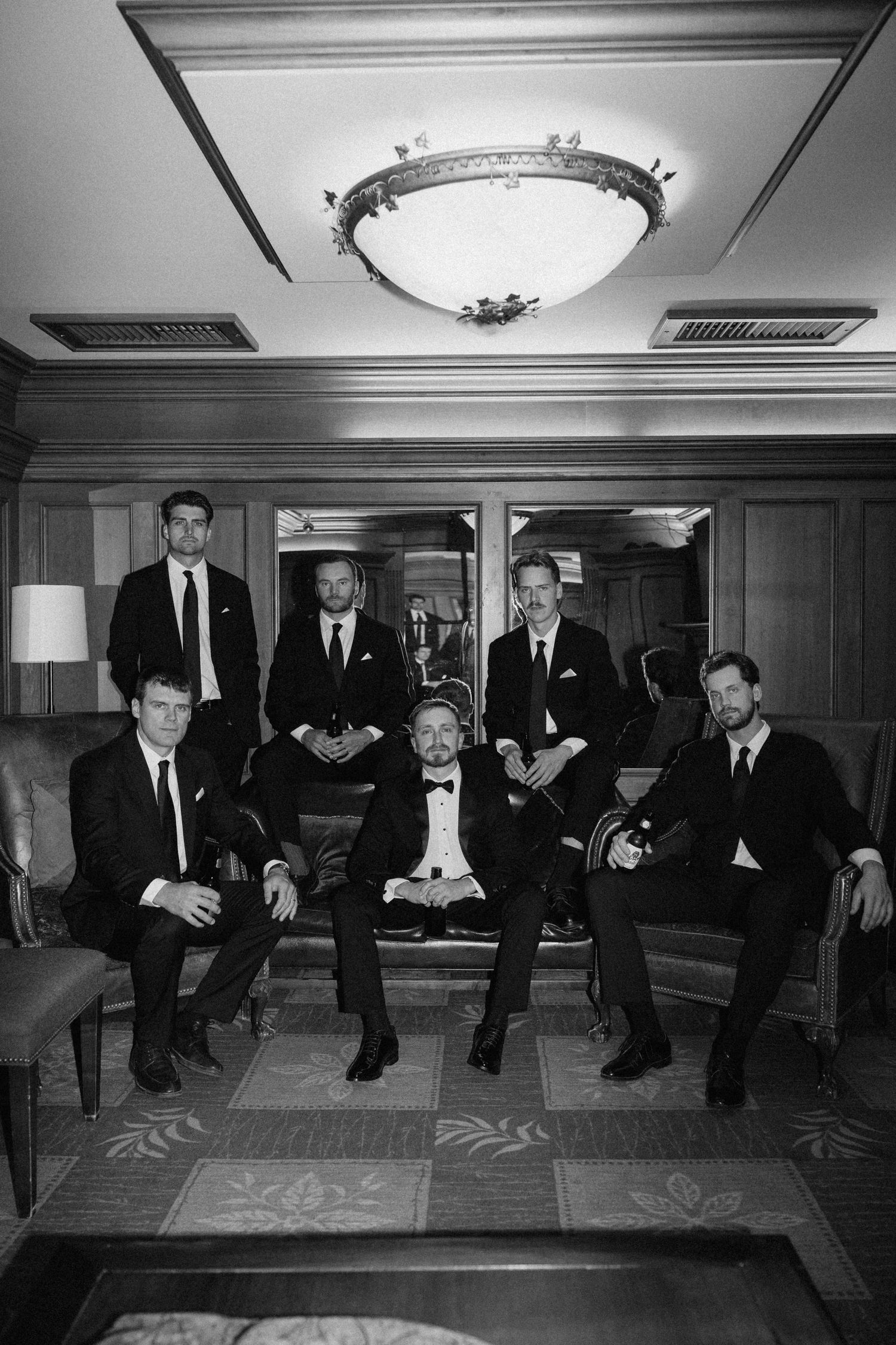 Groom and groomsmen posing in black tuxedos in an elegant room, black and white photo at Pillar and Post.