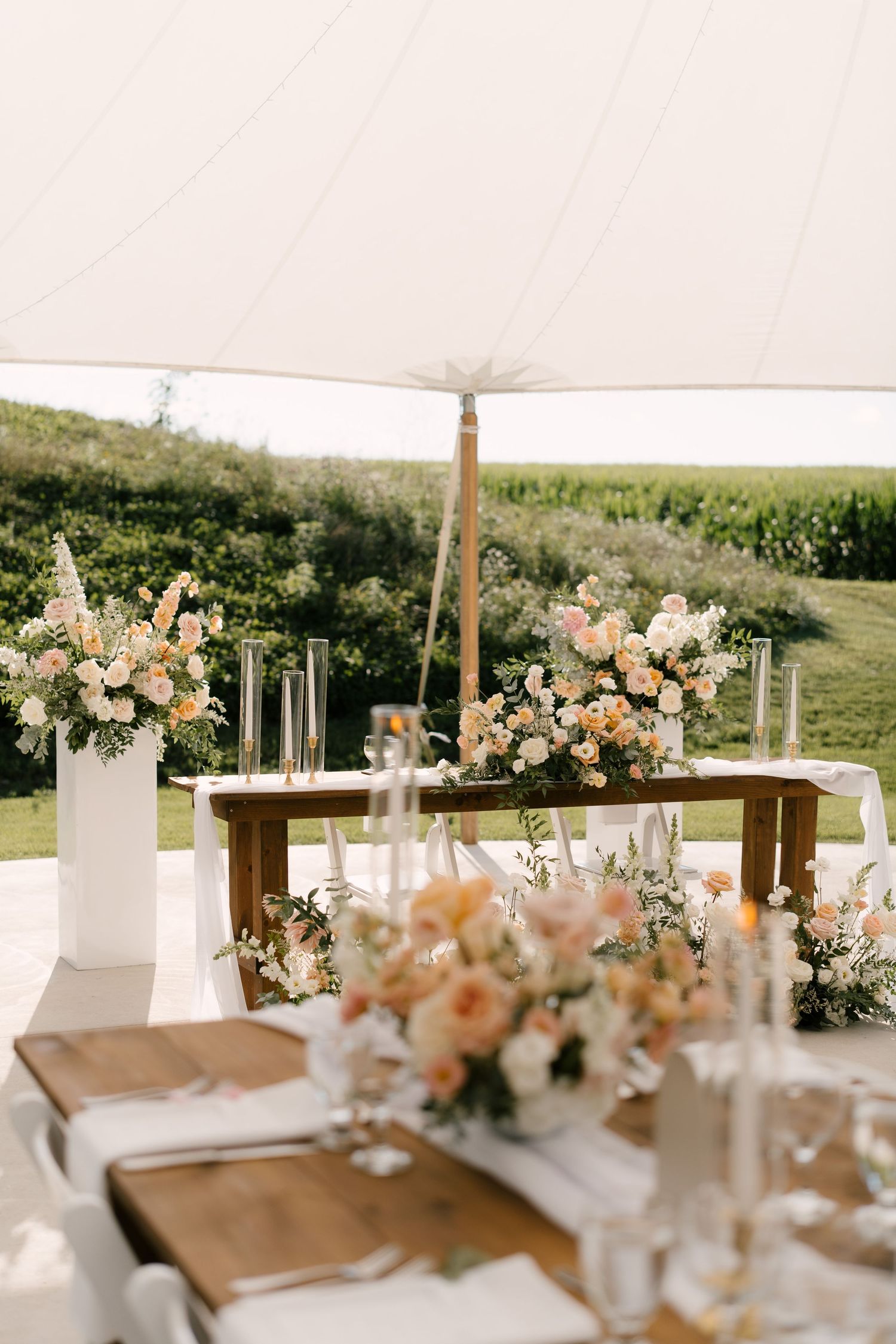 Elegant outdoor Wakefield Estates wedding reception table with peach and white floral arrangements under a white tent.