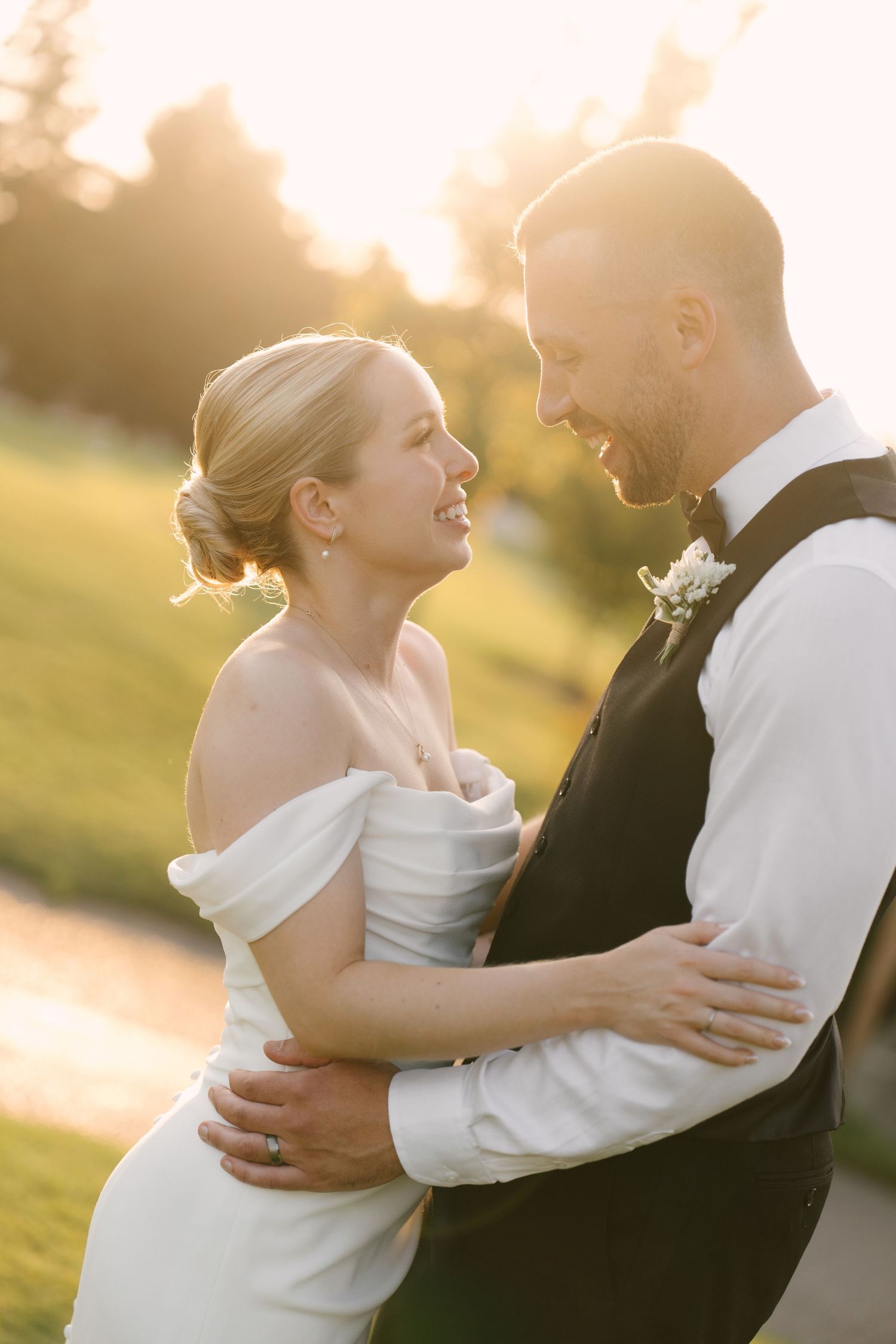Bride and groom share a joyful embrace bathed in golden sunset light during their wedding portraits at Guelph Golf Club.