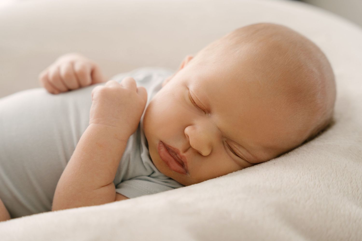 Close-up of serene newborn baby sleeping soundly on a cream pillow.
